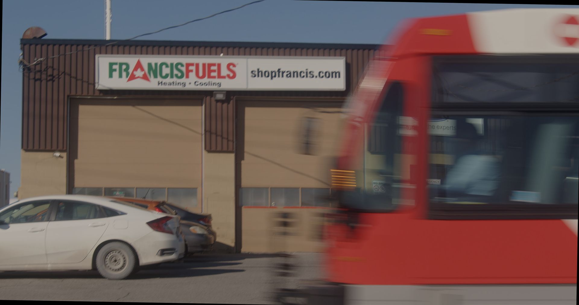 A white car is parked in front of a building that says francisfuels