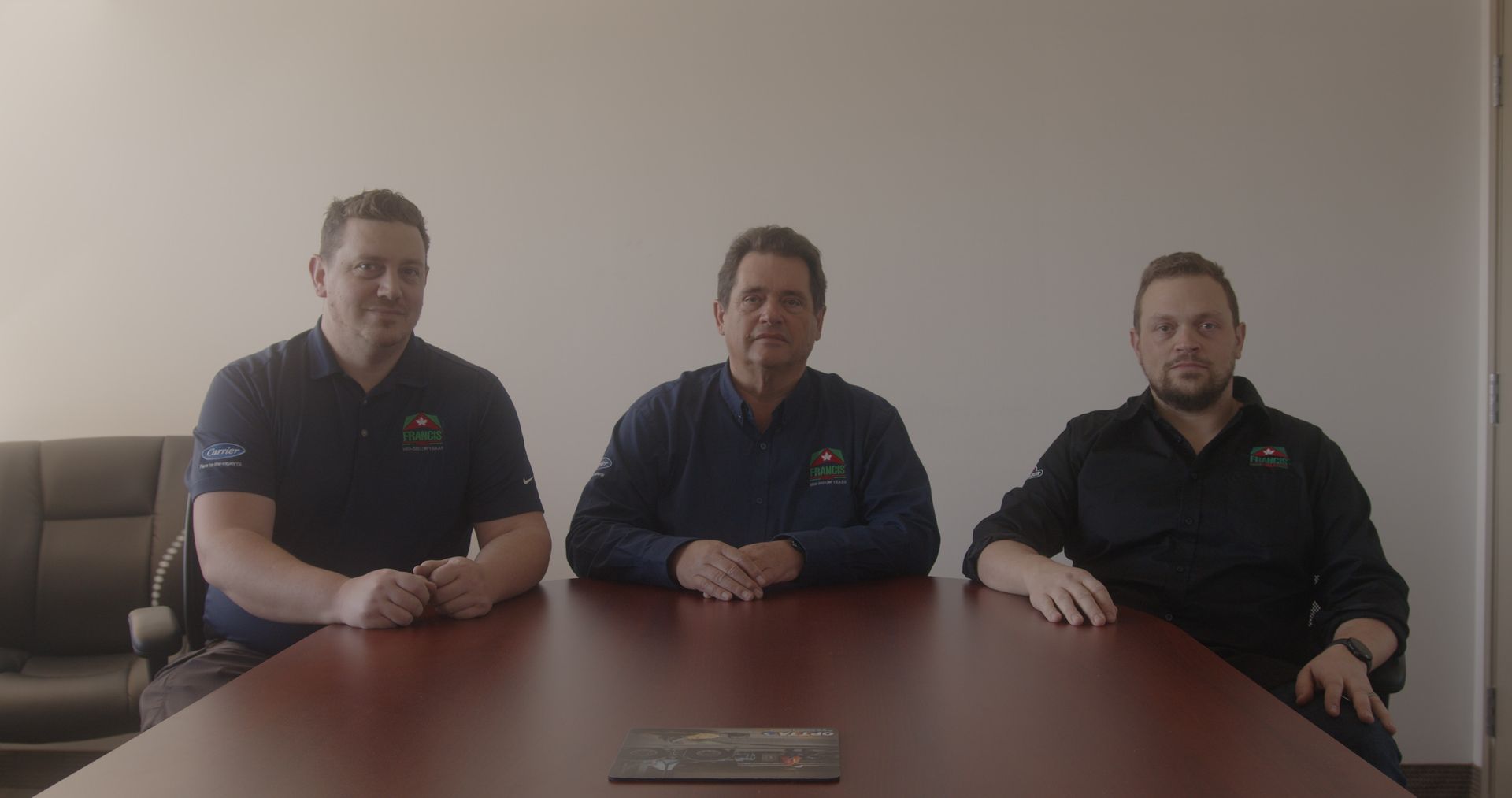 Three men are sitting at a table in a conference room.