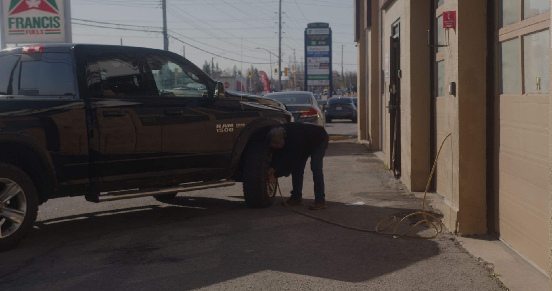 A man is changing a tire on a truck in front of a franco 's restaurant.