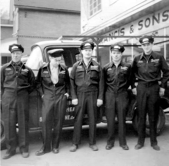 A group of men standing in front of a building that says francis & sons