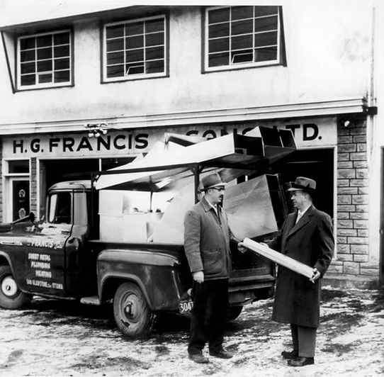 Two men are standing in front of a building that says h.g. francis