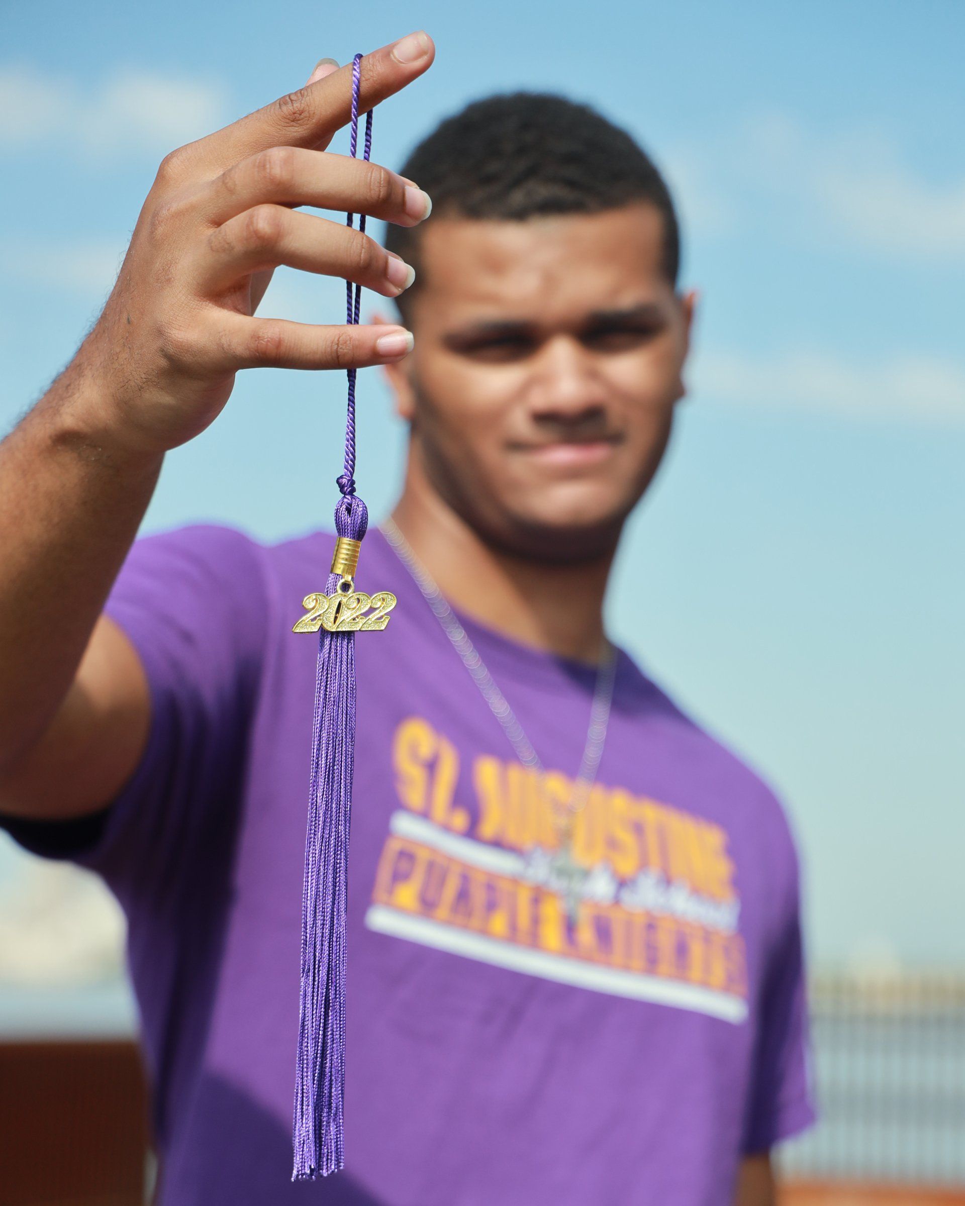 A man in a purple shirt is holding a purple tassel