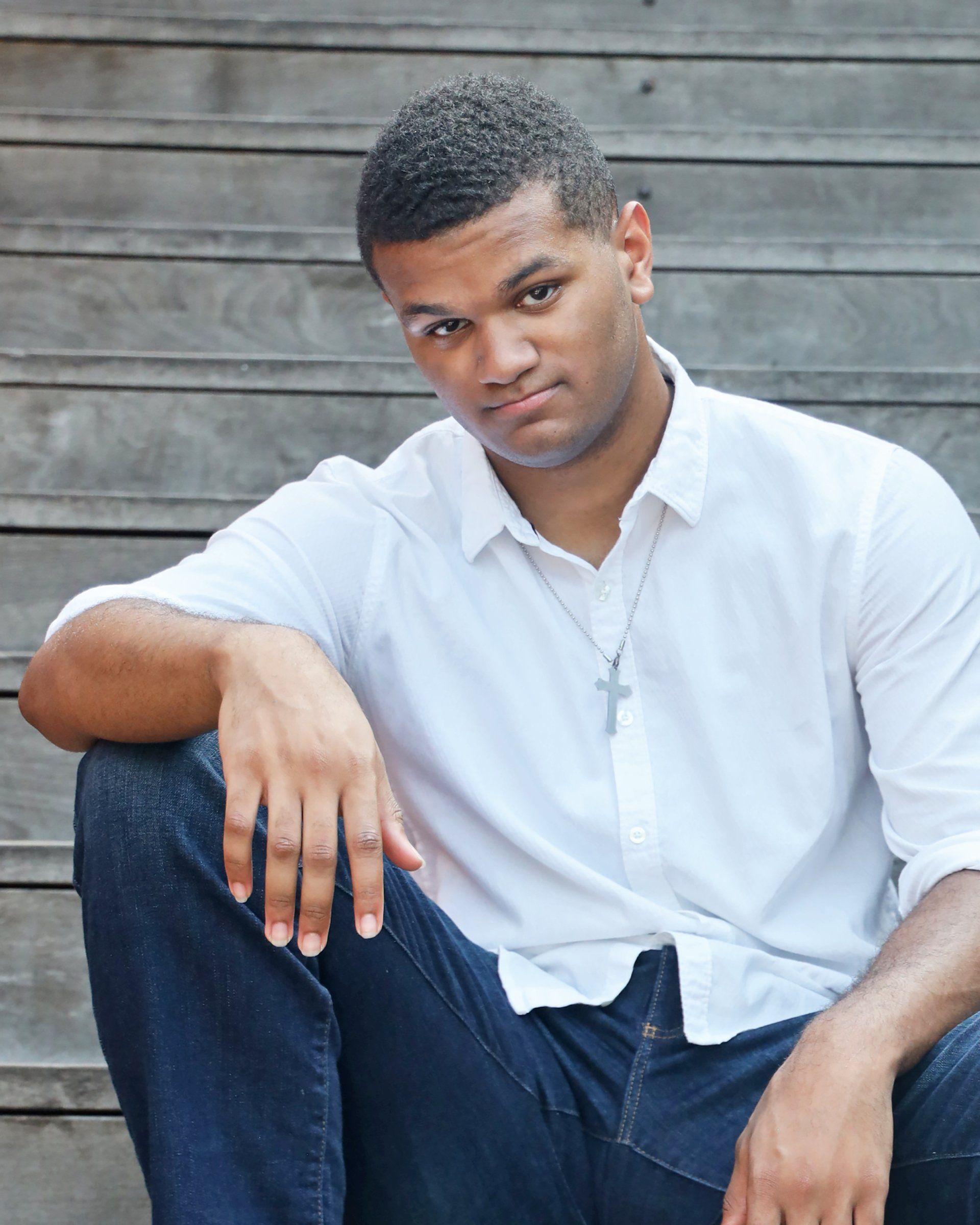 A man in a white shirt is sitting on a set of wooden stairs
