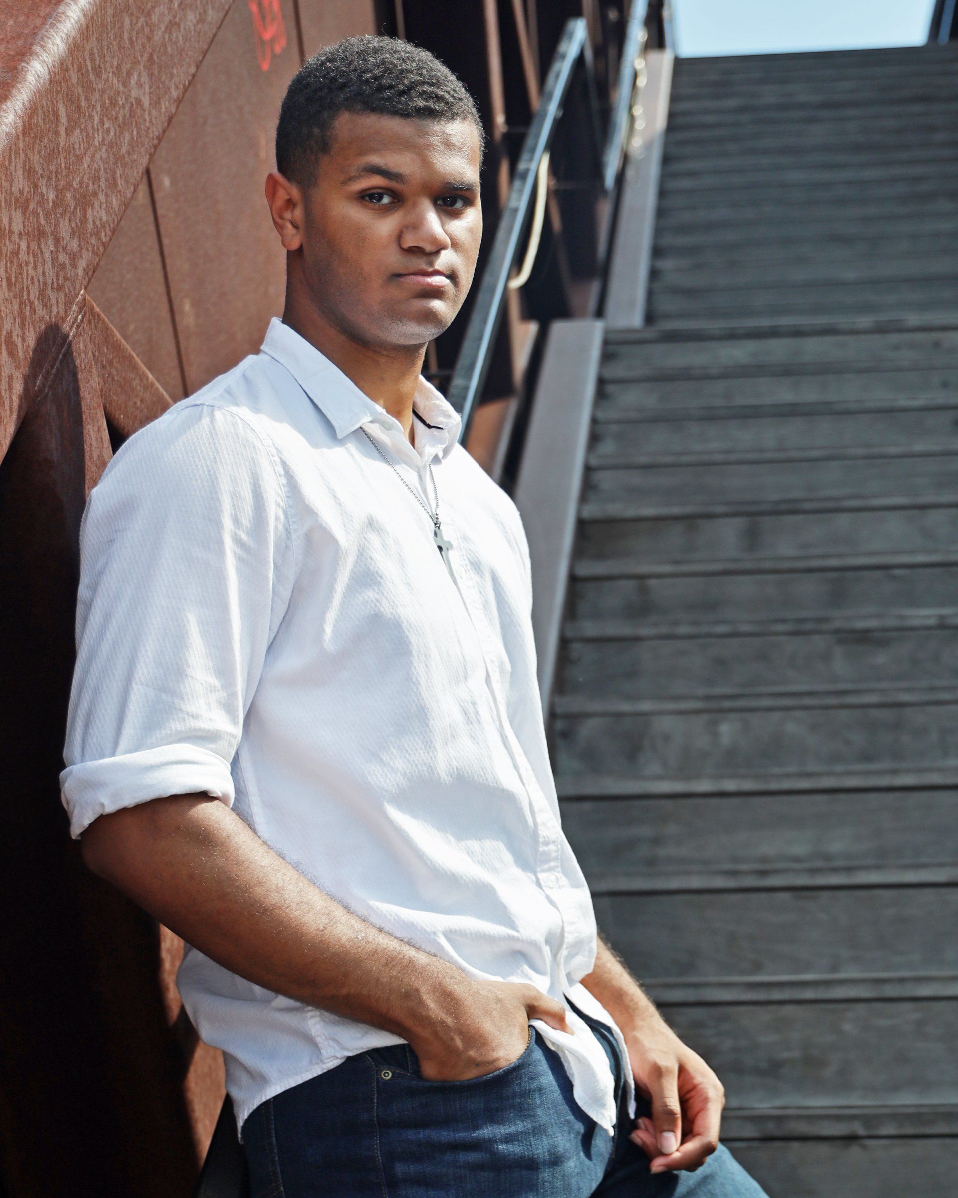 A man leaning against a wall with his hands in his pockets