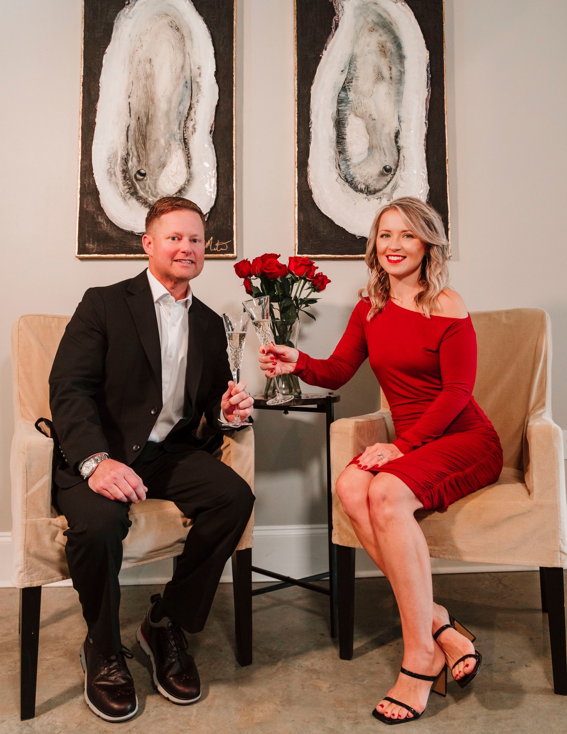 A man and a woman are sitting in chairs holding glasses of champagne.