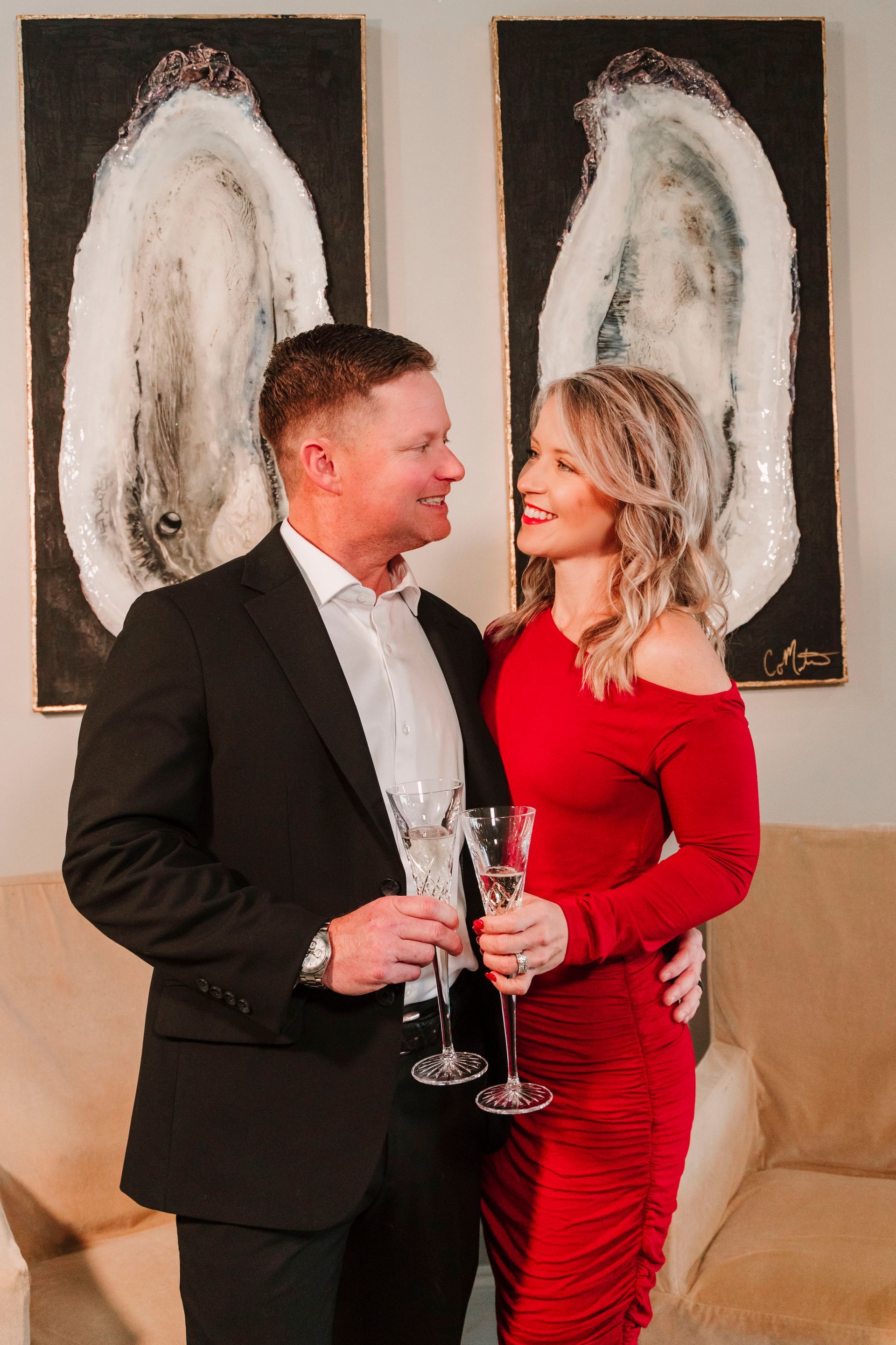 A man and a woman are standing next to each other holding champagne glasses.