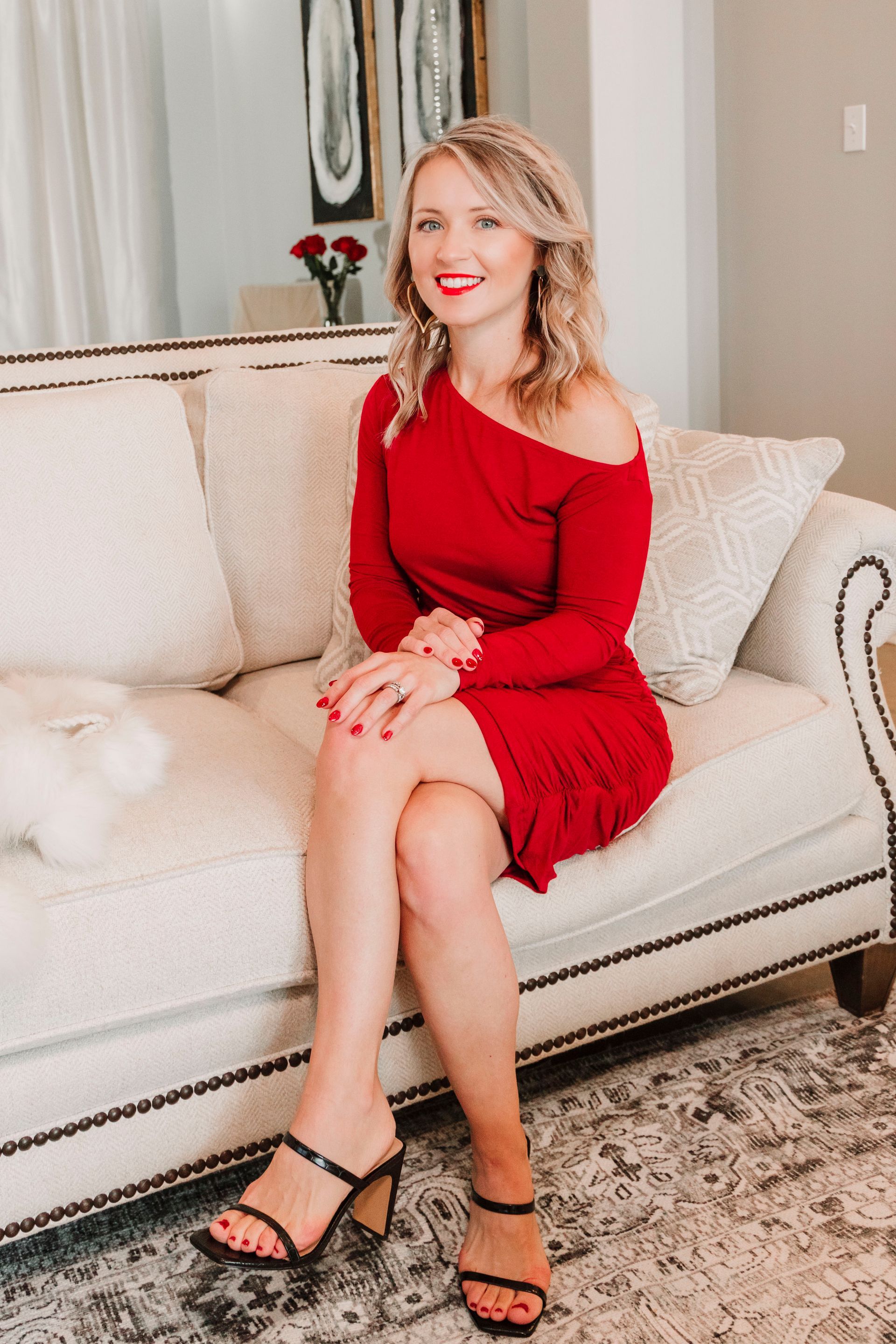A woman in a red dress is sitting on a white couch.