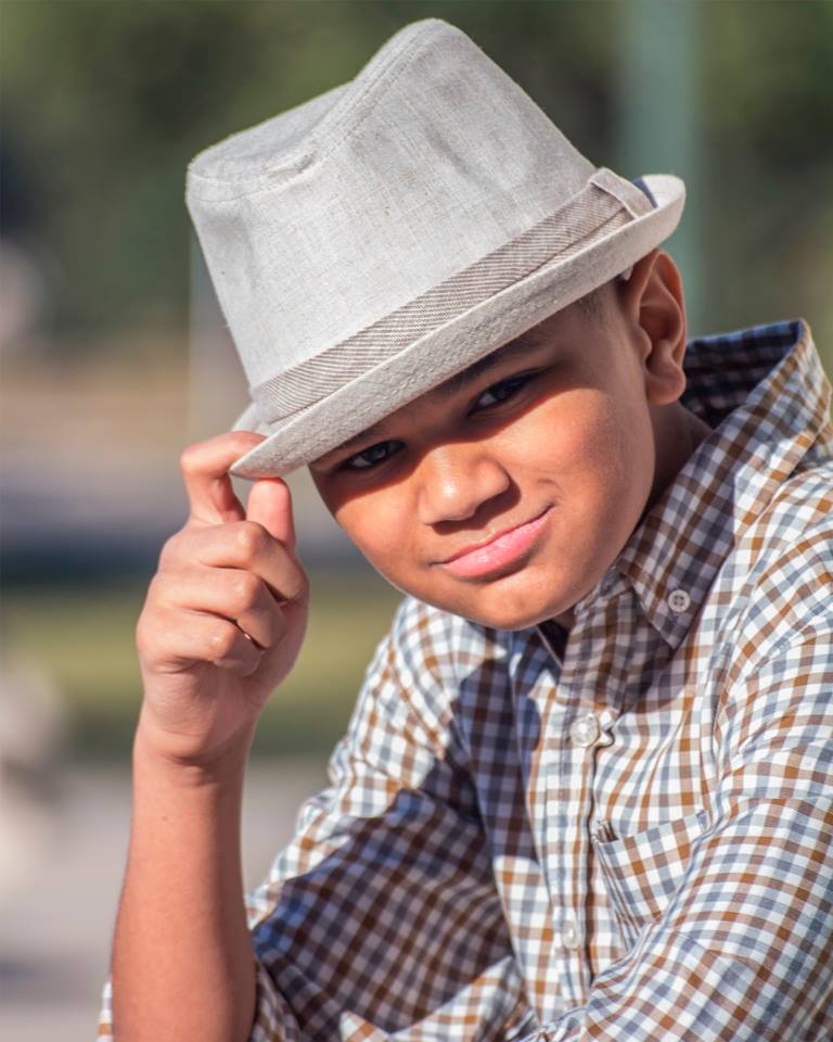 A young boy wearing a hat and a plaid shirt
