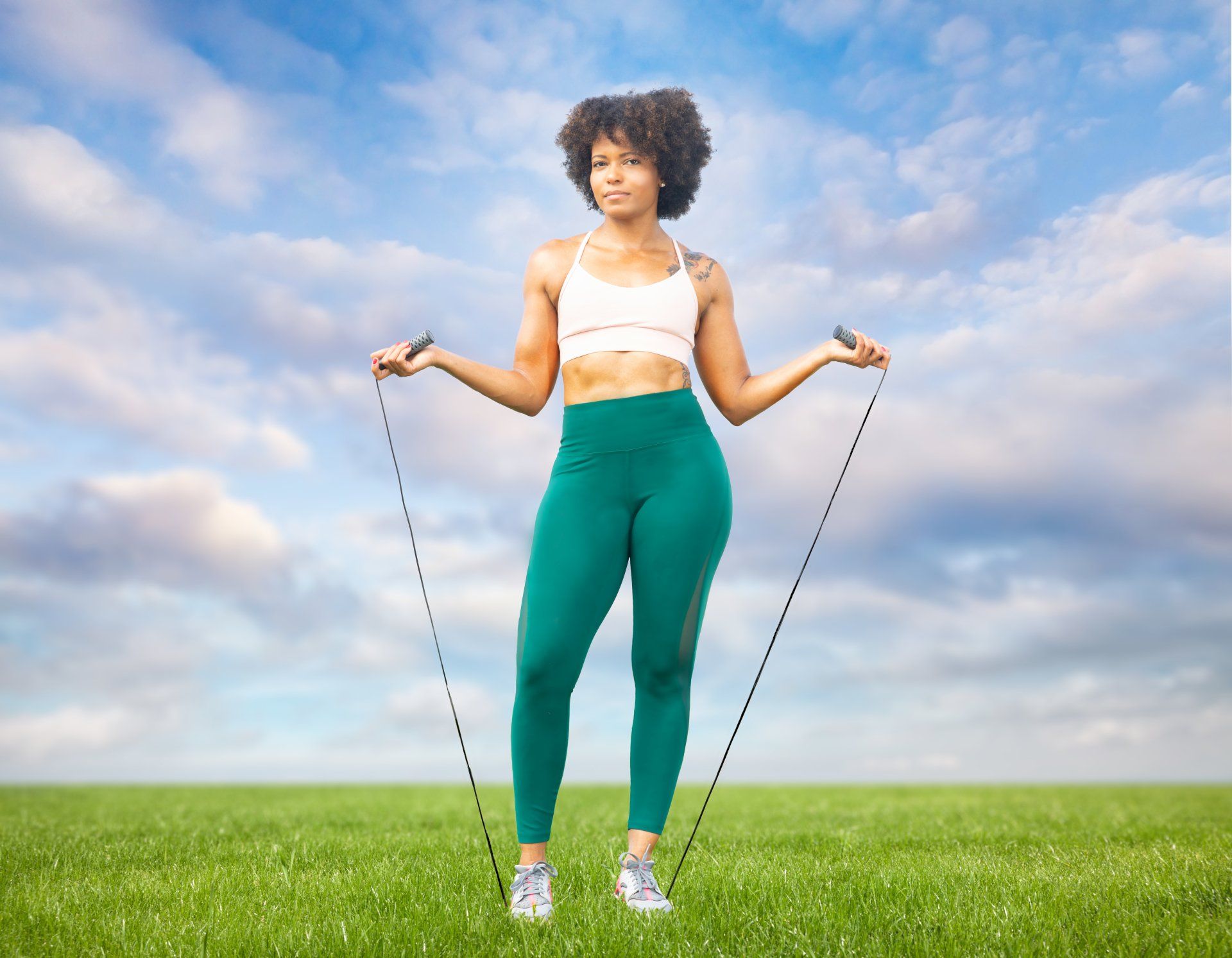 A woman is jumping a jump rope in a field.