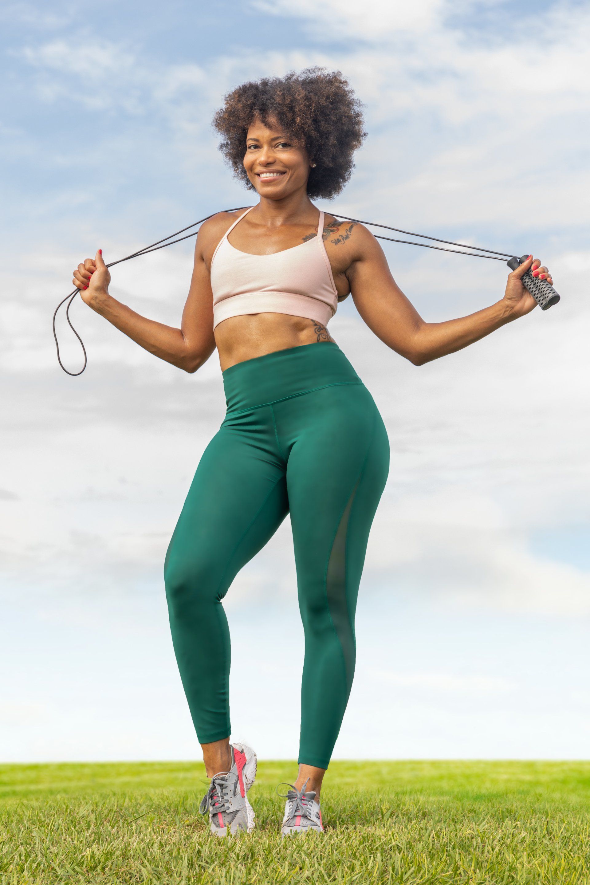 A woman is jumping a jump rope in a field.
