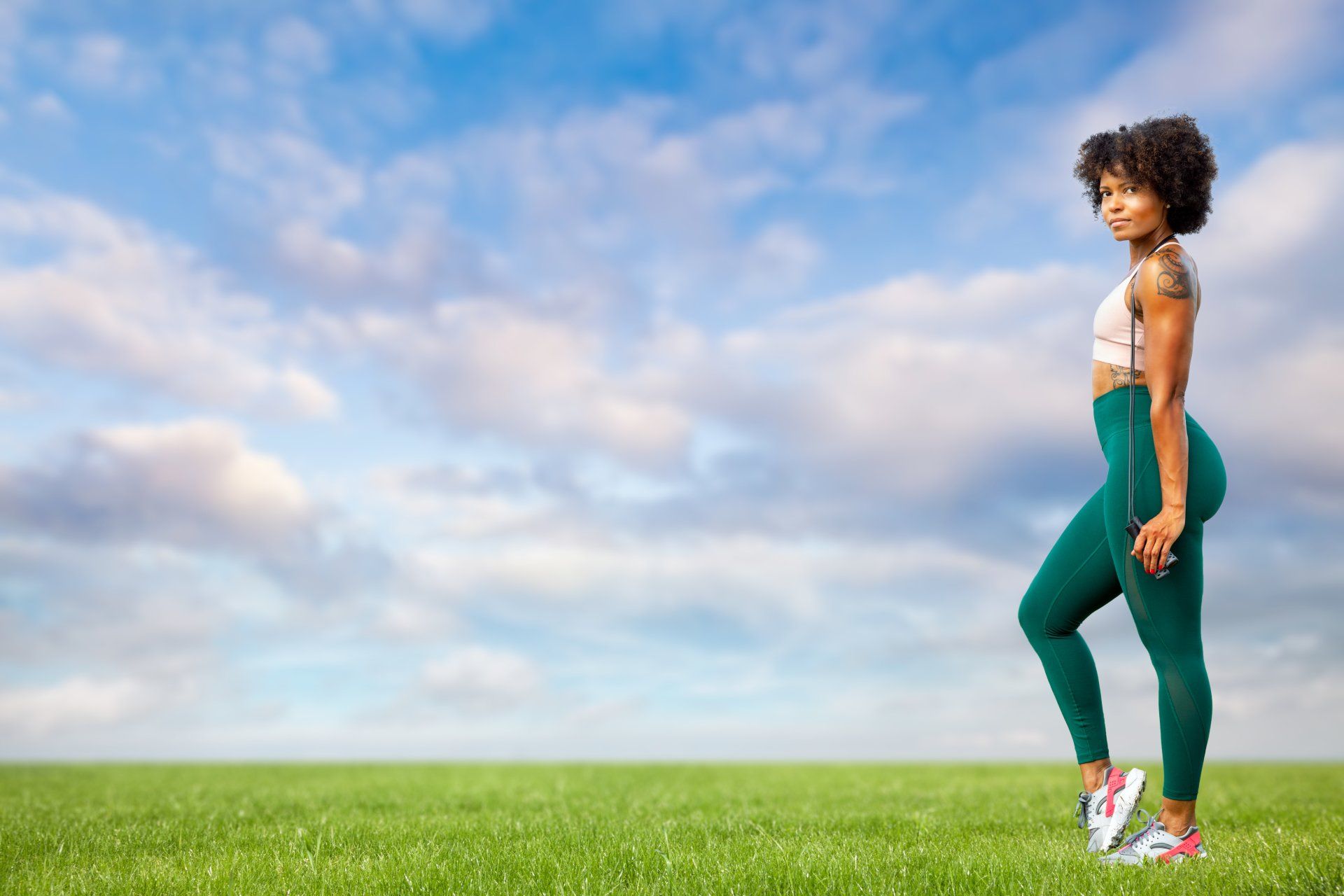 A woman is standing on one leg in a grassy field.
