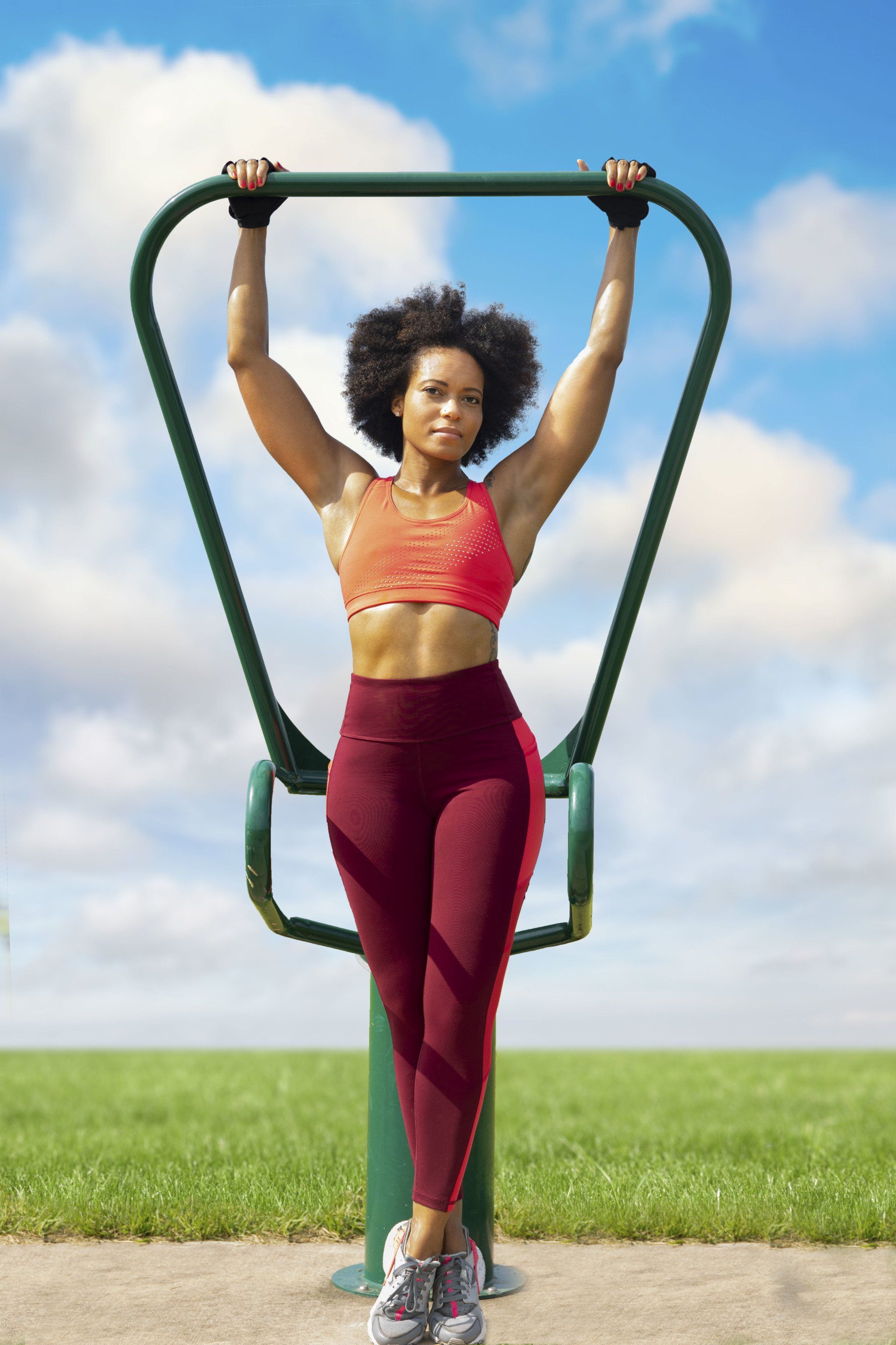 A woman is doing exercises on a machine in a park.