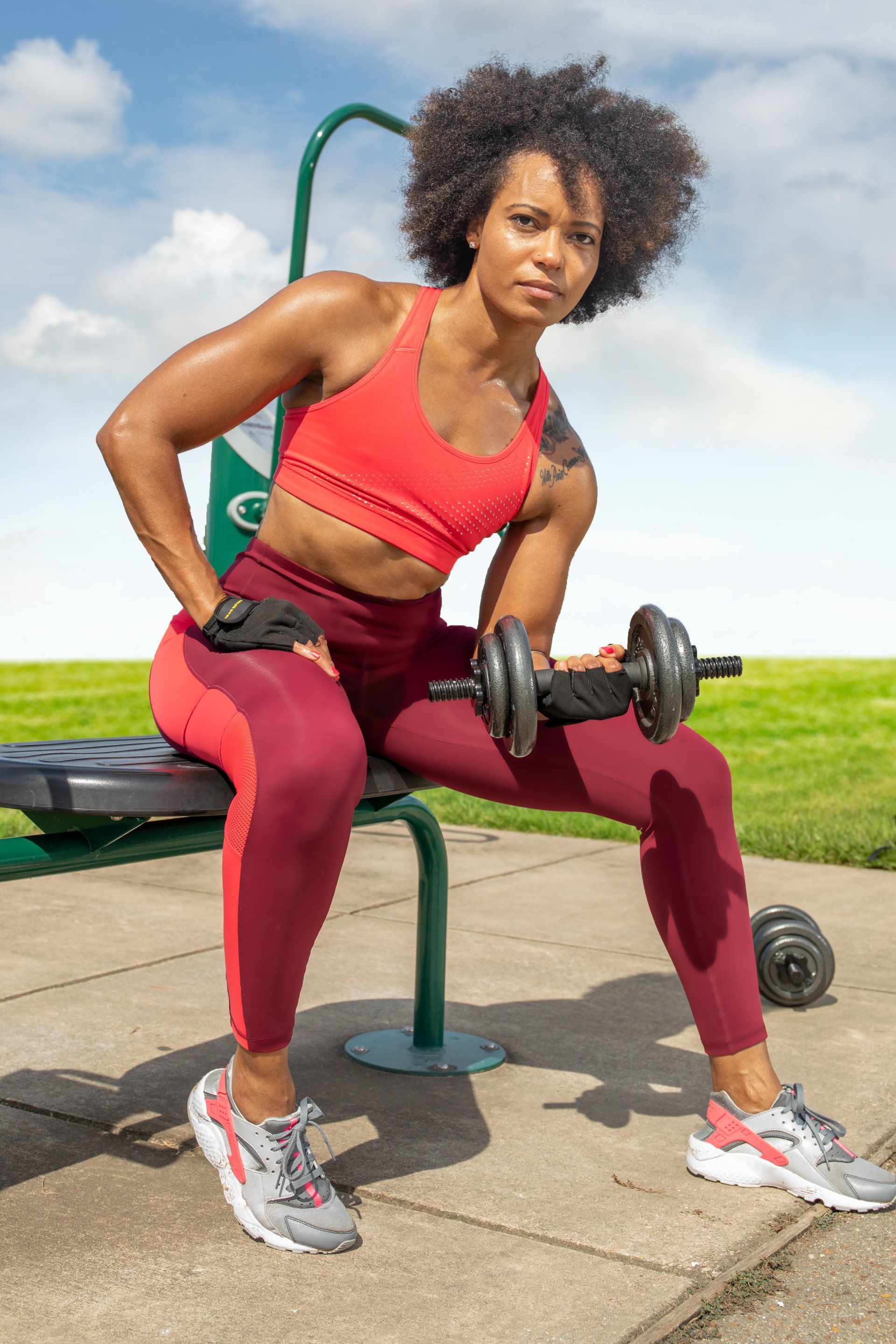 A woman is sitting on a bench holding a dumbbell.