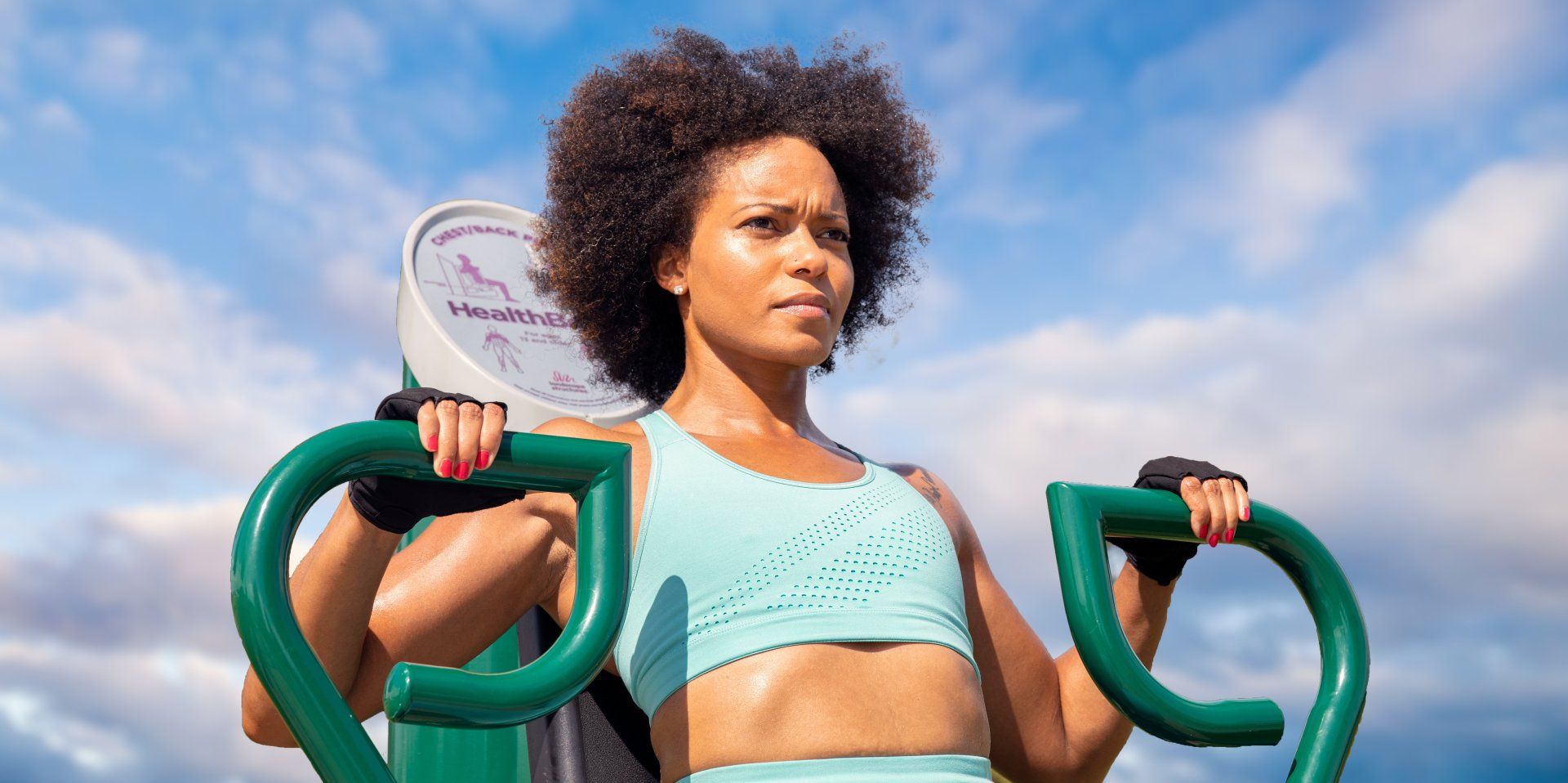 A woman is doing exercises on a machine outside.