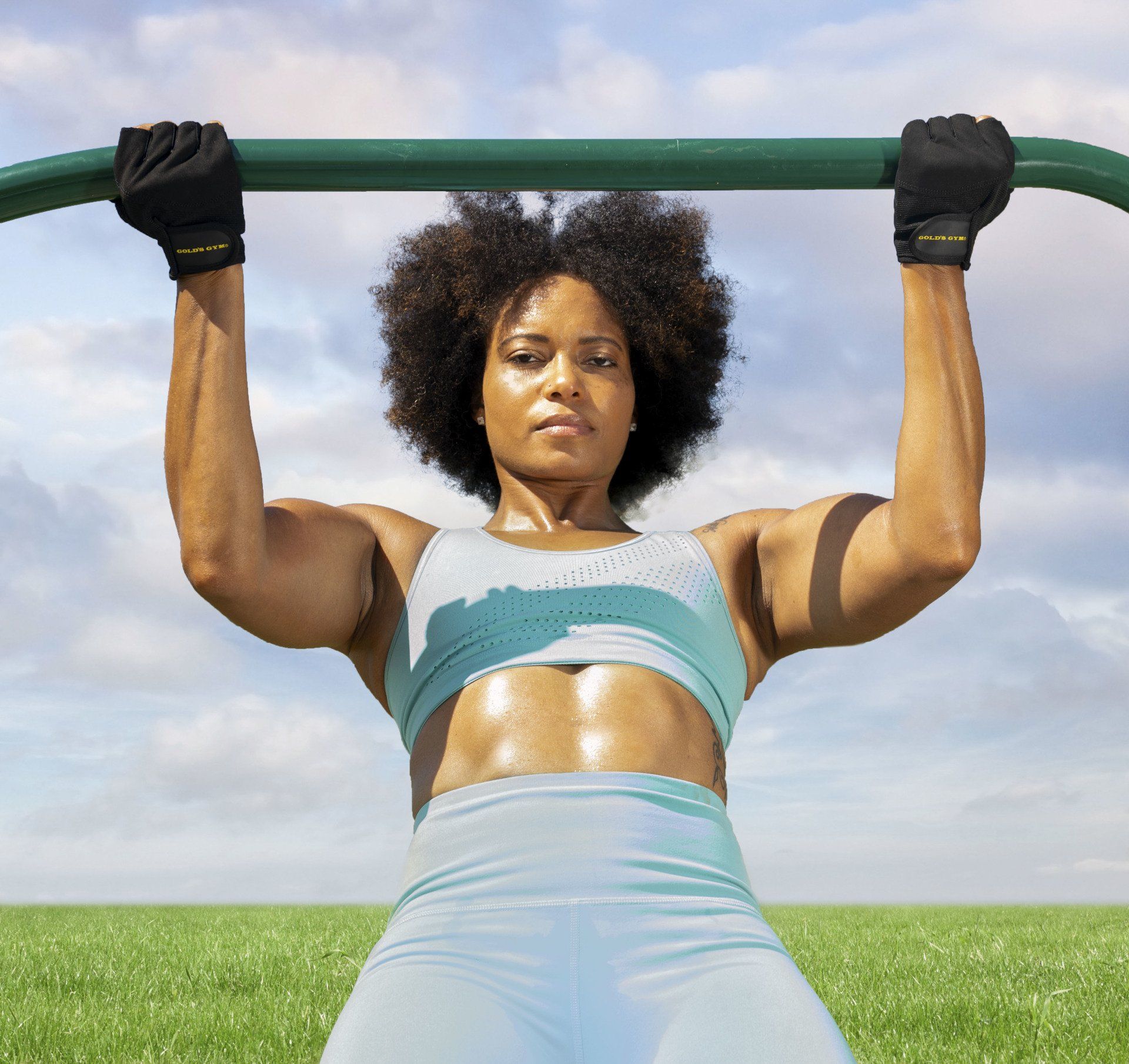 A woman is doing pull ups on a bar in a field