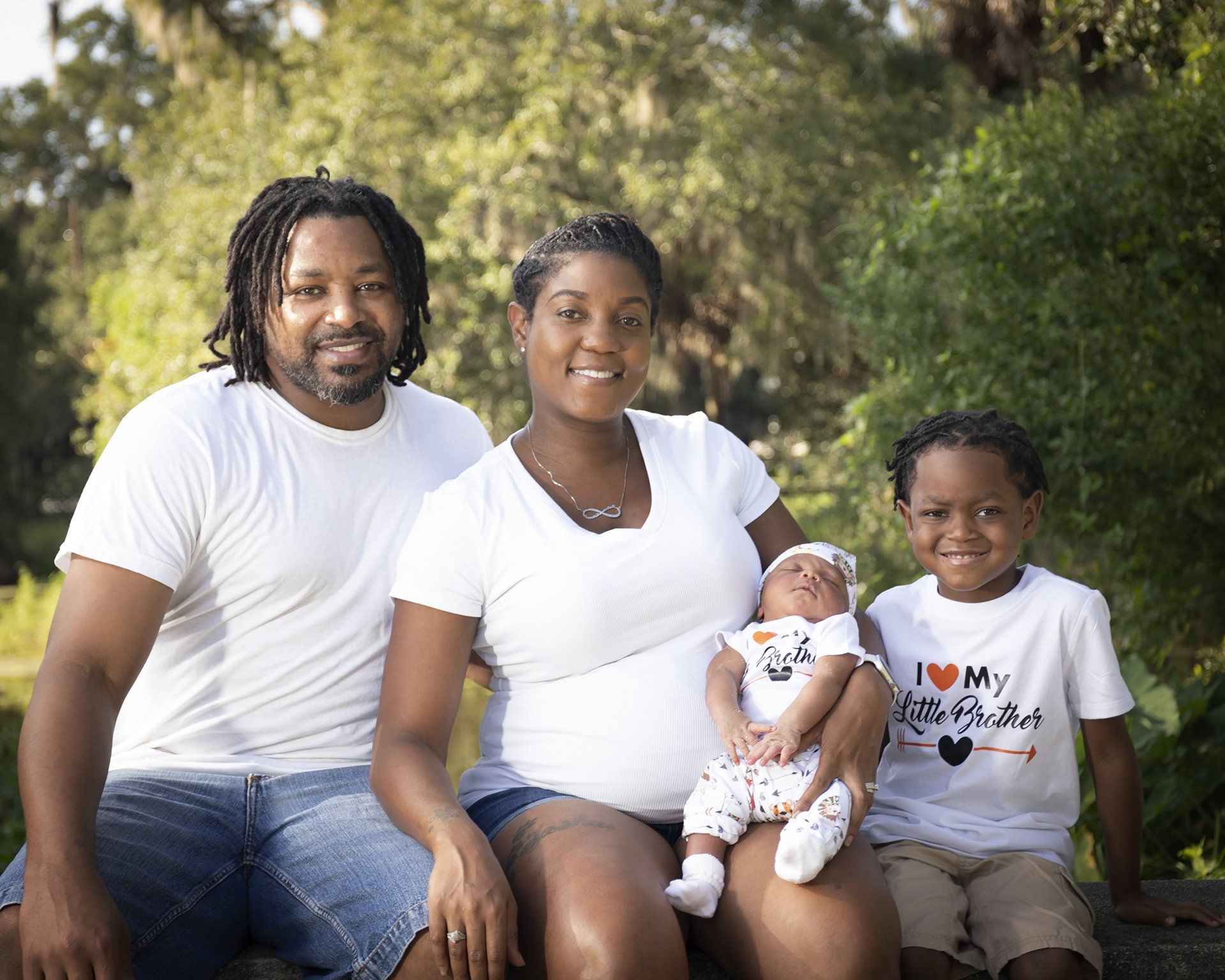 A family is posing for a picture while sitting on a rock.