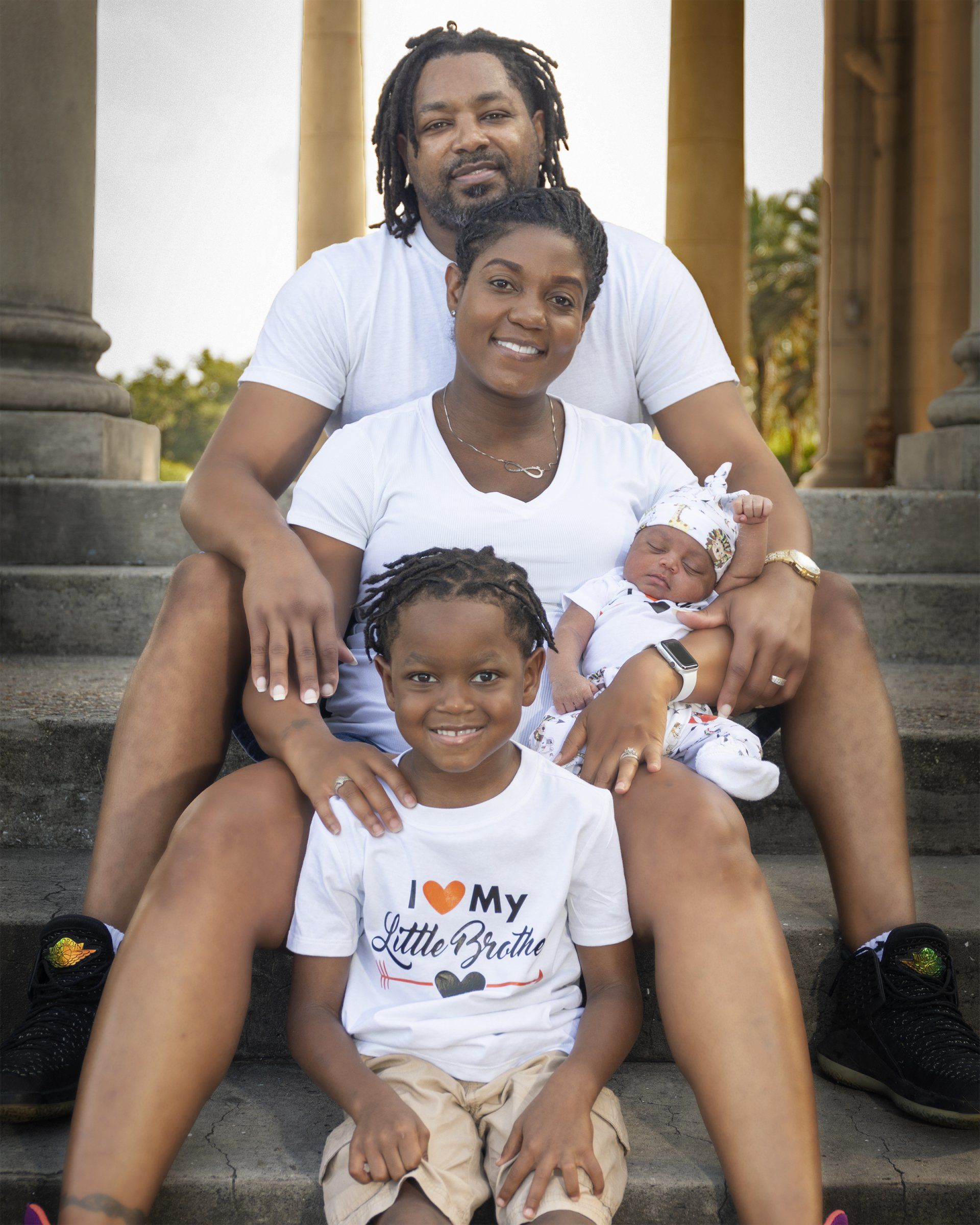 A family is posing for a picture and one of the children is wearing a shirt that says i love my little brother