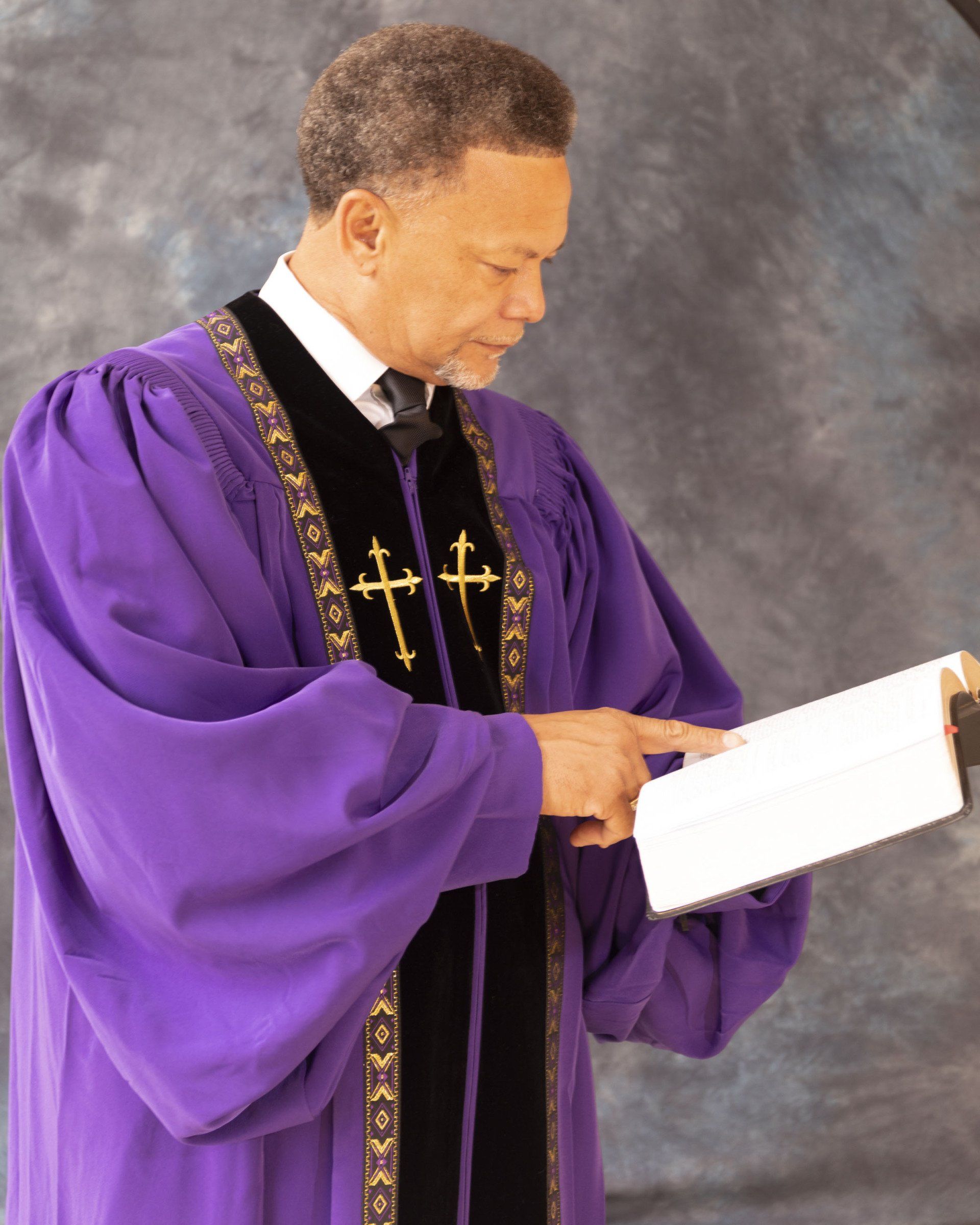 A man in a purple robe is reading a book