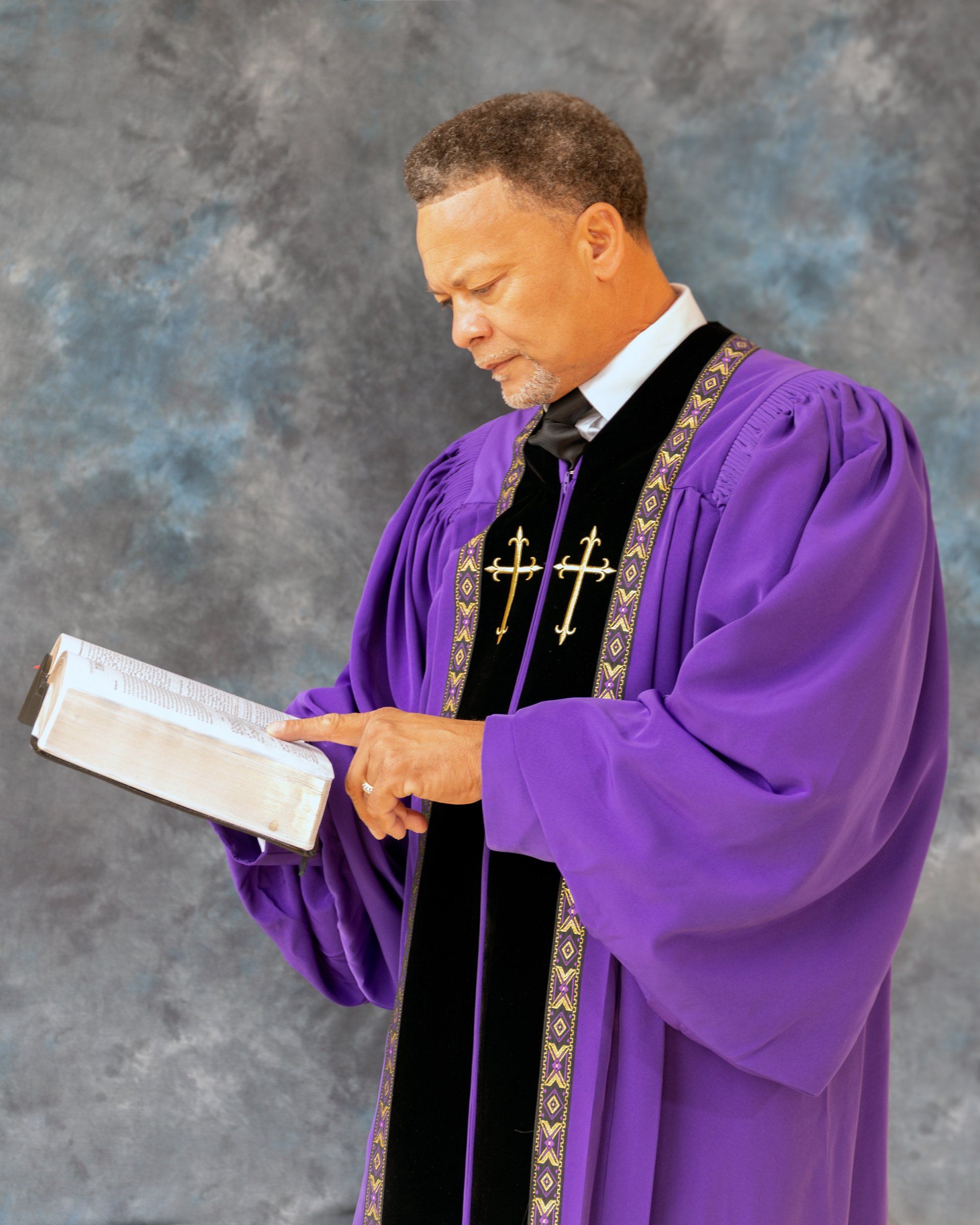 A man in a purple robe is reading a bible