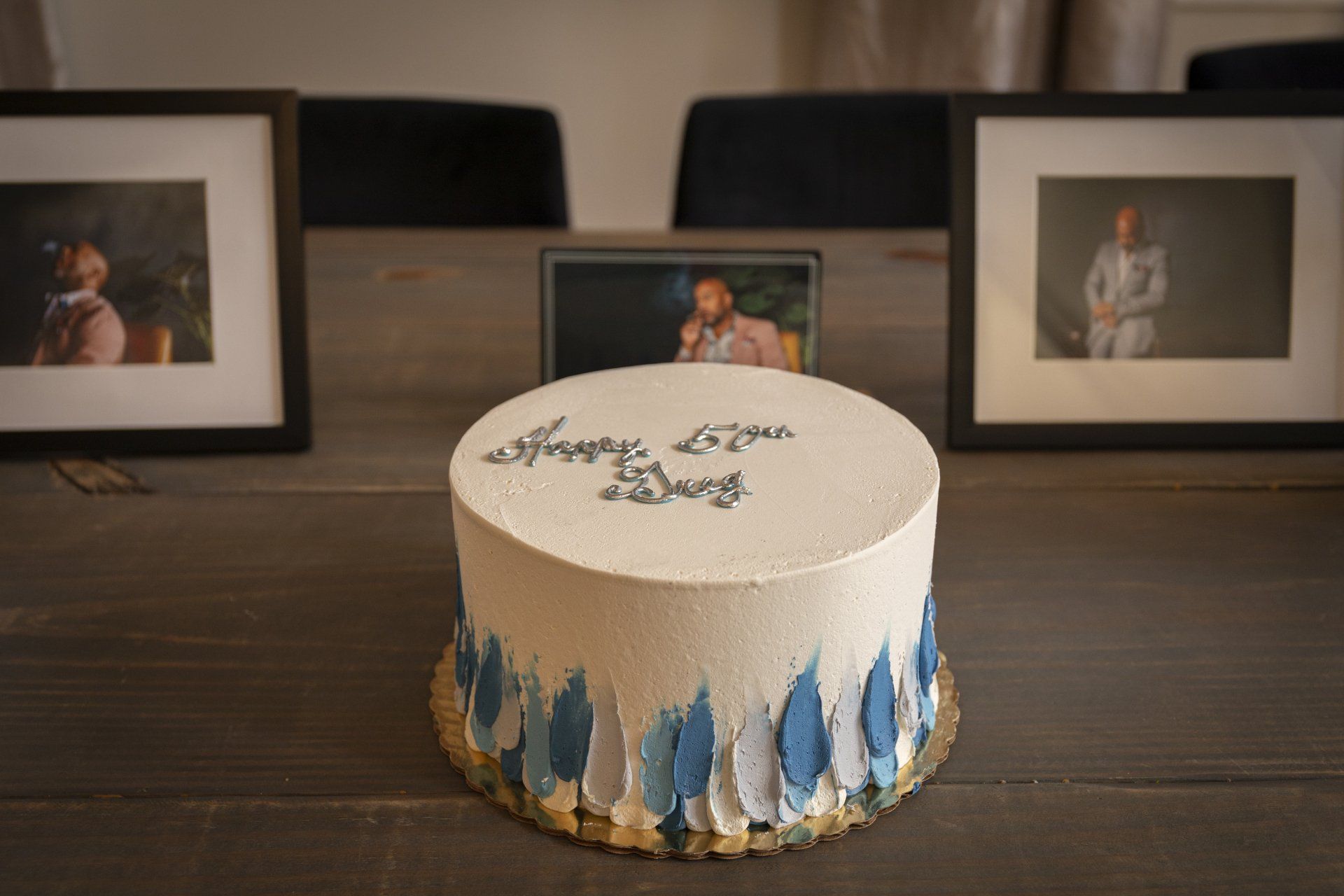 A white cake with blue frosting is sitting on a wooden table.
