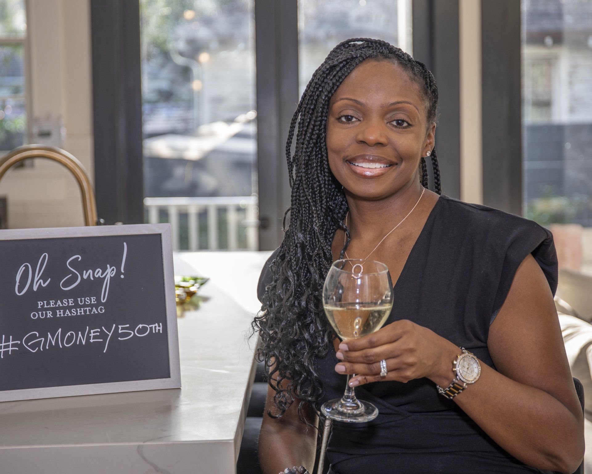 A woman is sitting at a counter holding a glass of wine.