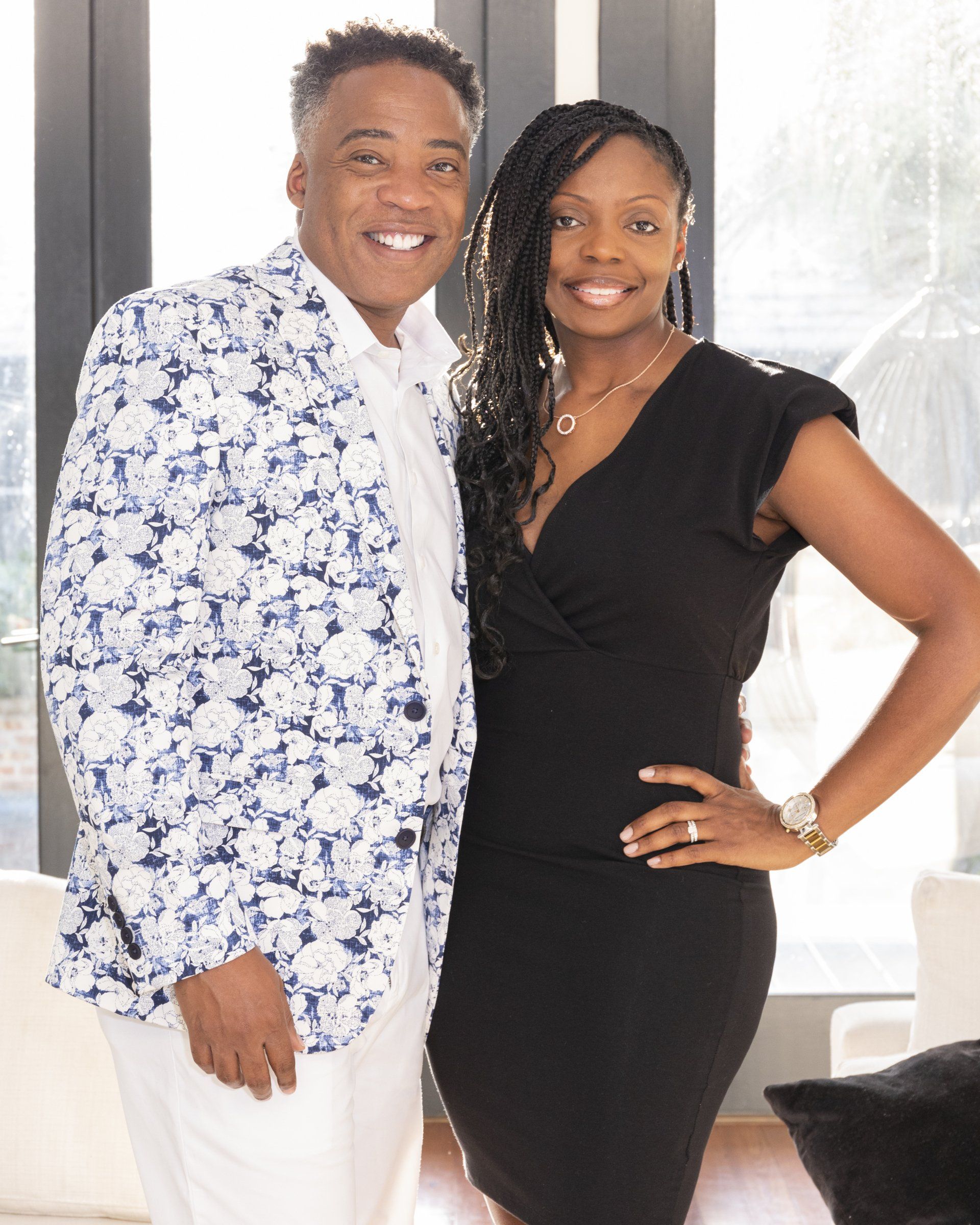 A man and a woman are posing for a picture in front of a window.