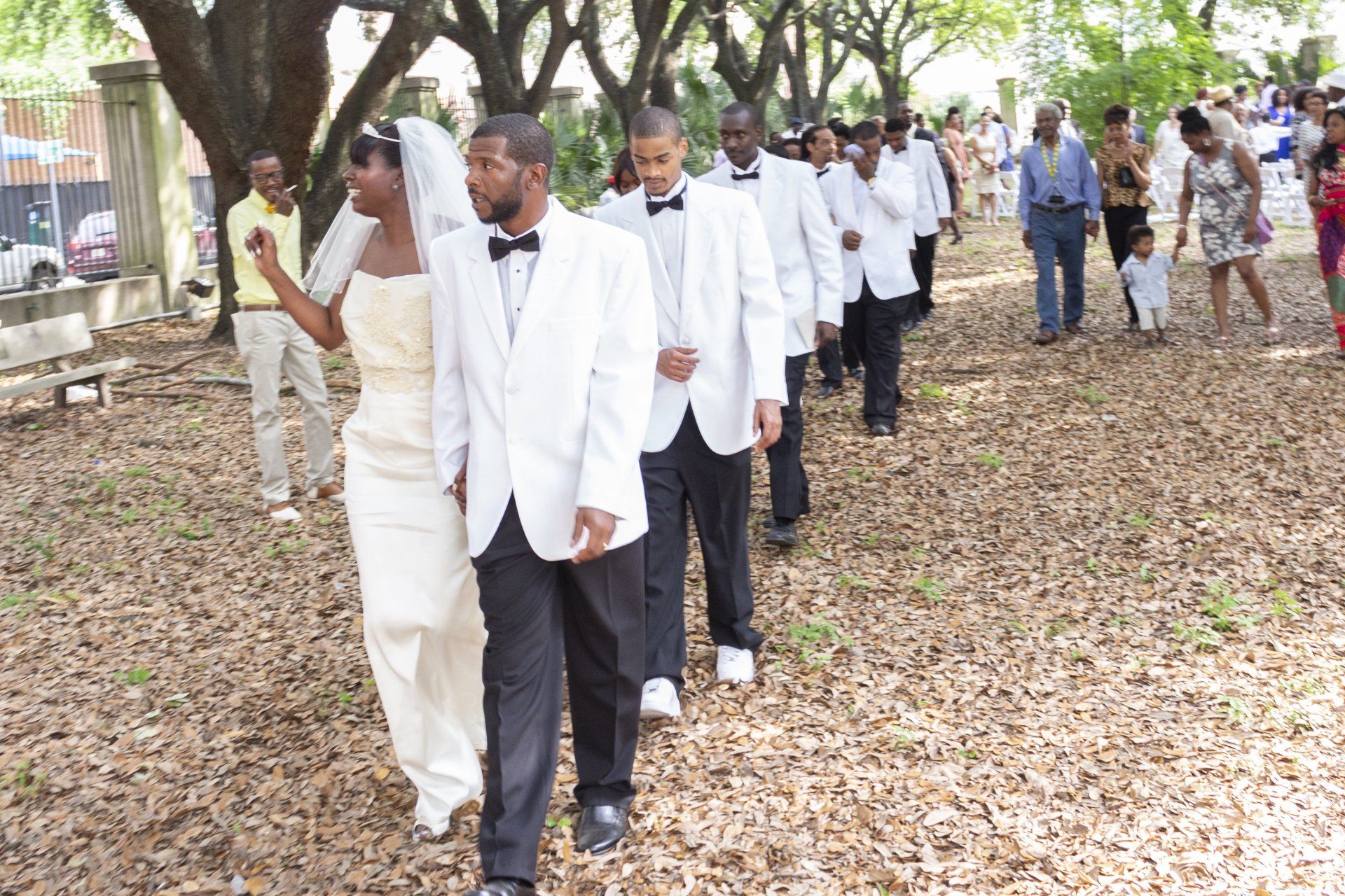 A bride and groom are walking with their wedding party