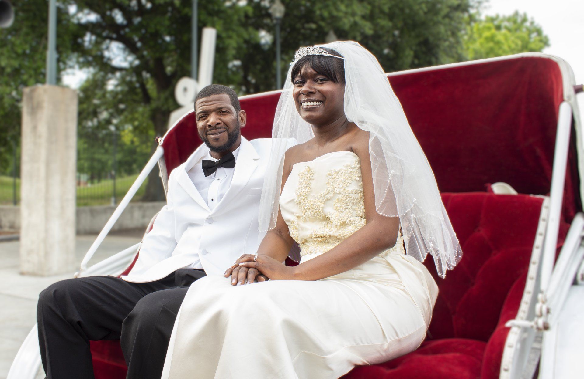 A bride and groom are sitting in a horse drawn carriage