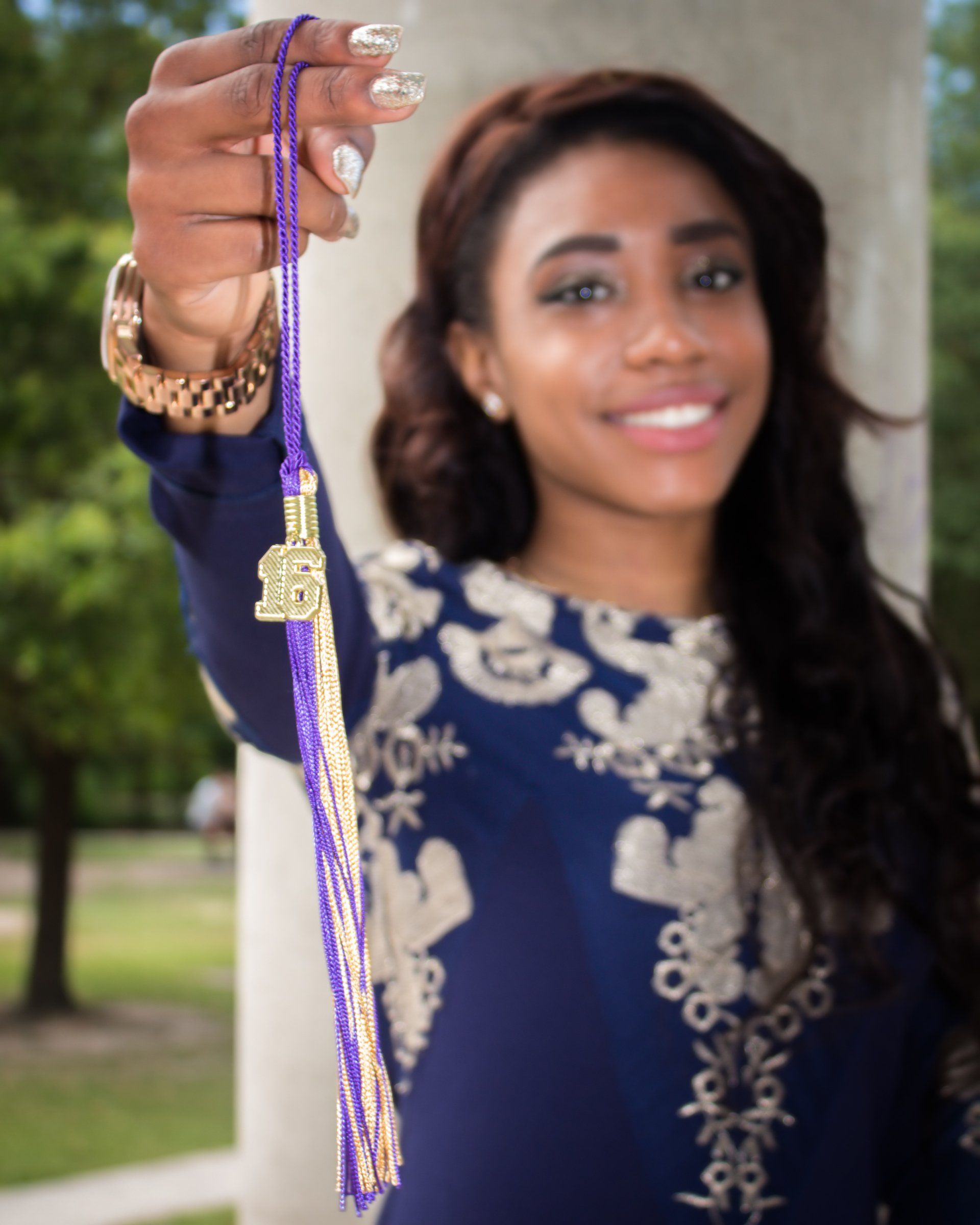 A woman in a blue dress is holding a purple tassel