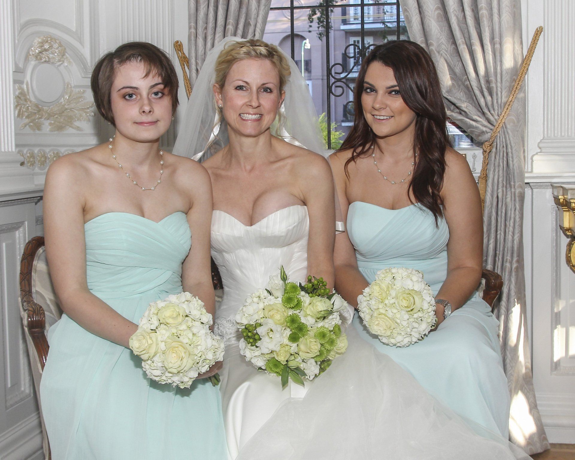 A bride and her two bridesmaids are posing for a picture