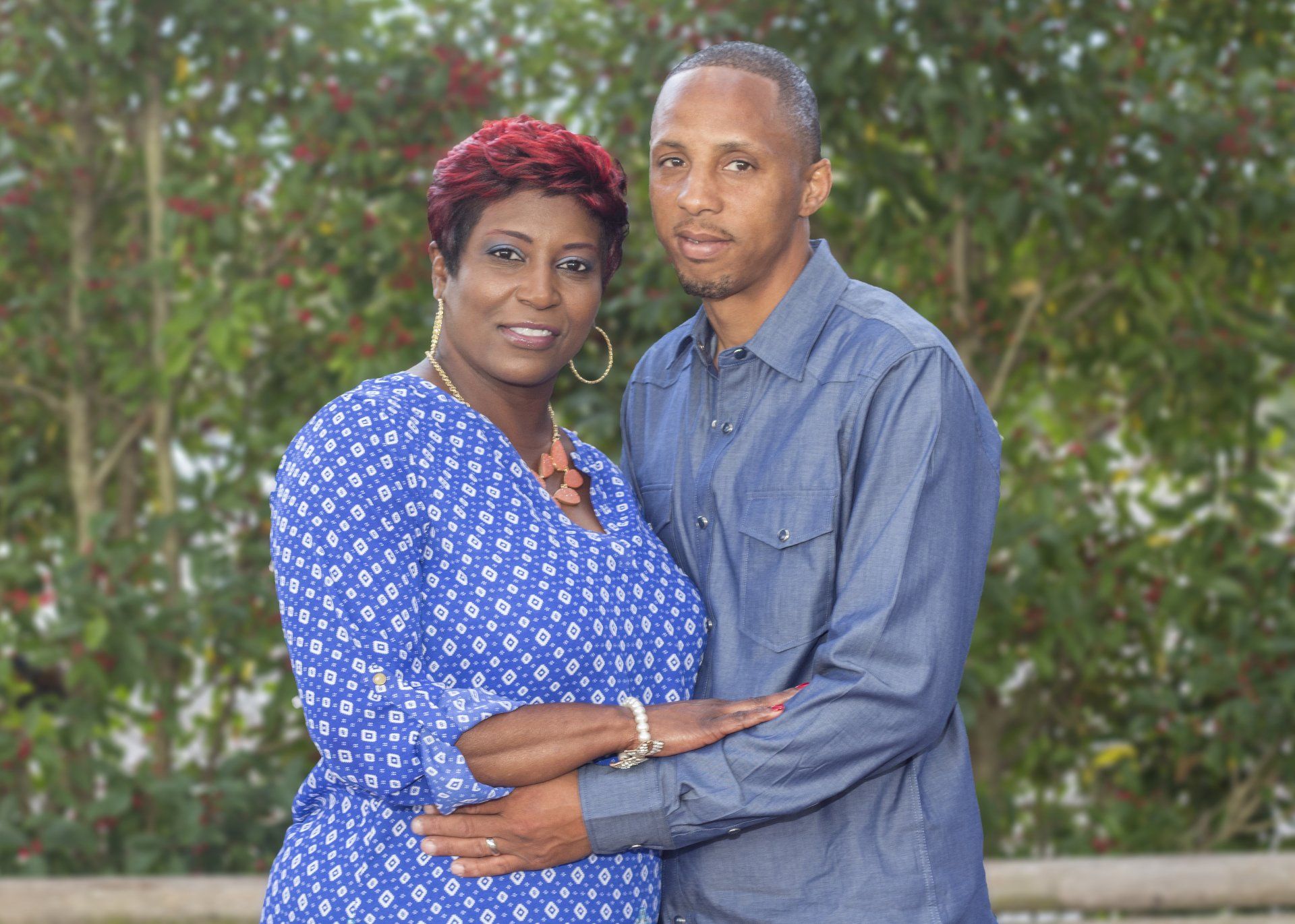 A man and a woman are posing for a picture together . the woman is wearing a blue dress.