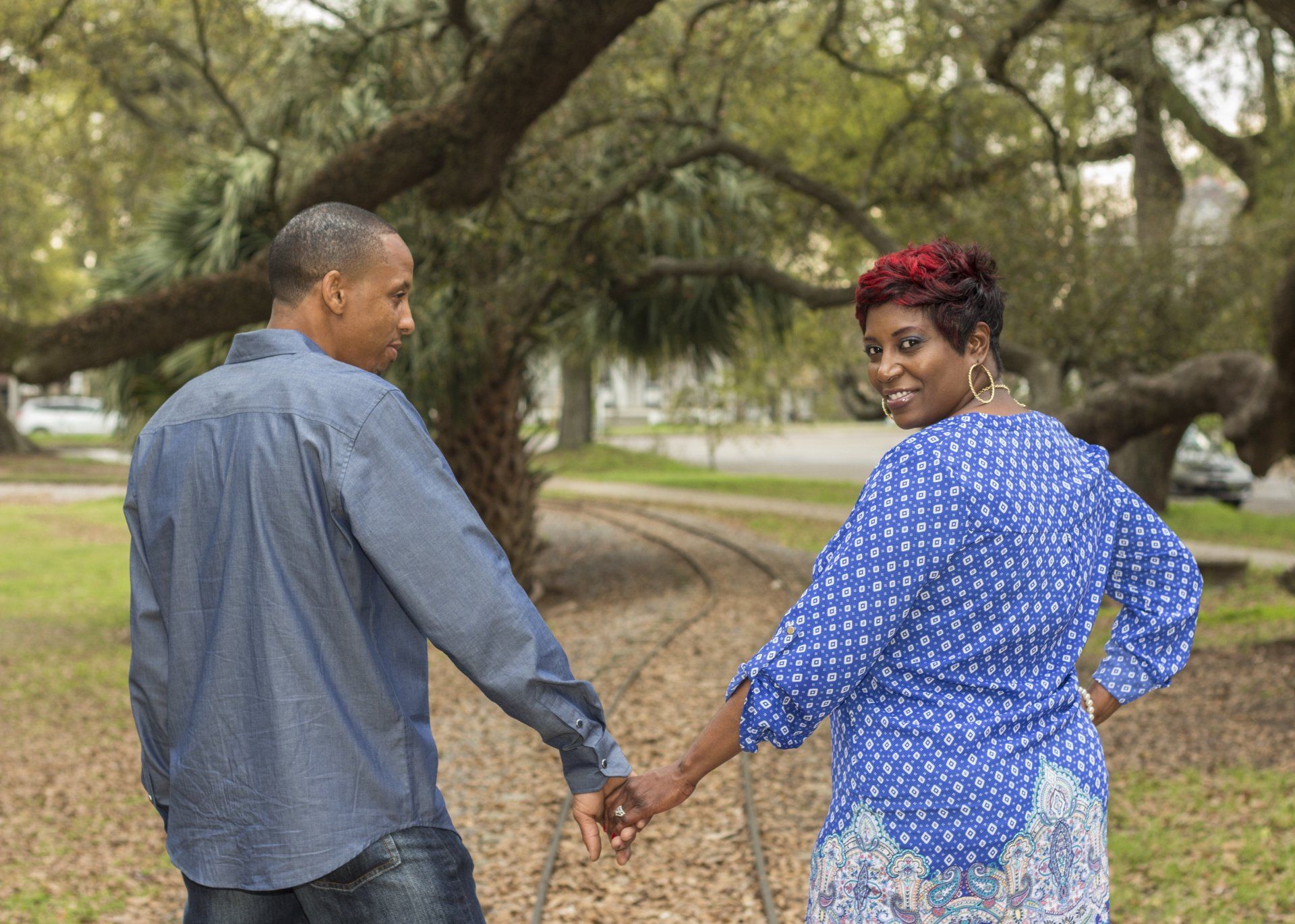 A man and a woman are holding hands in a park.