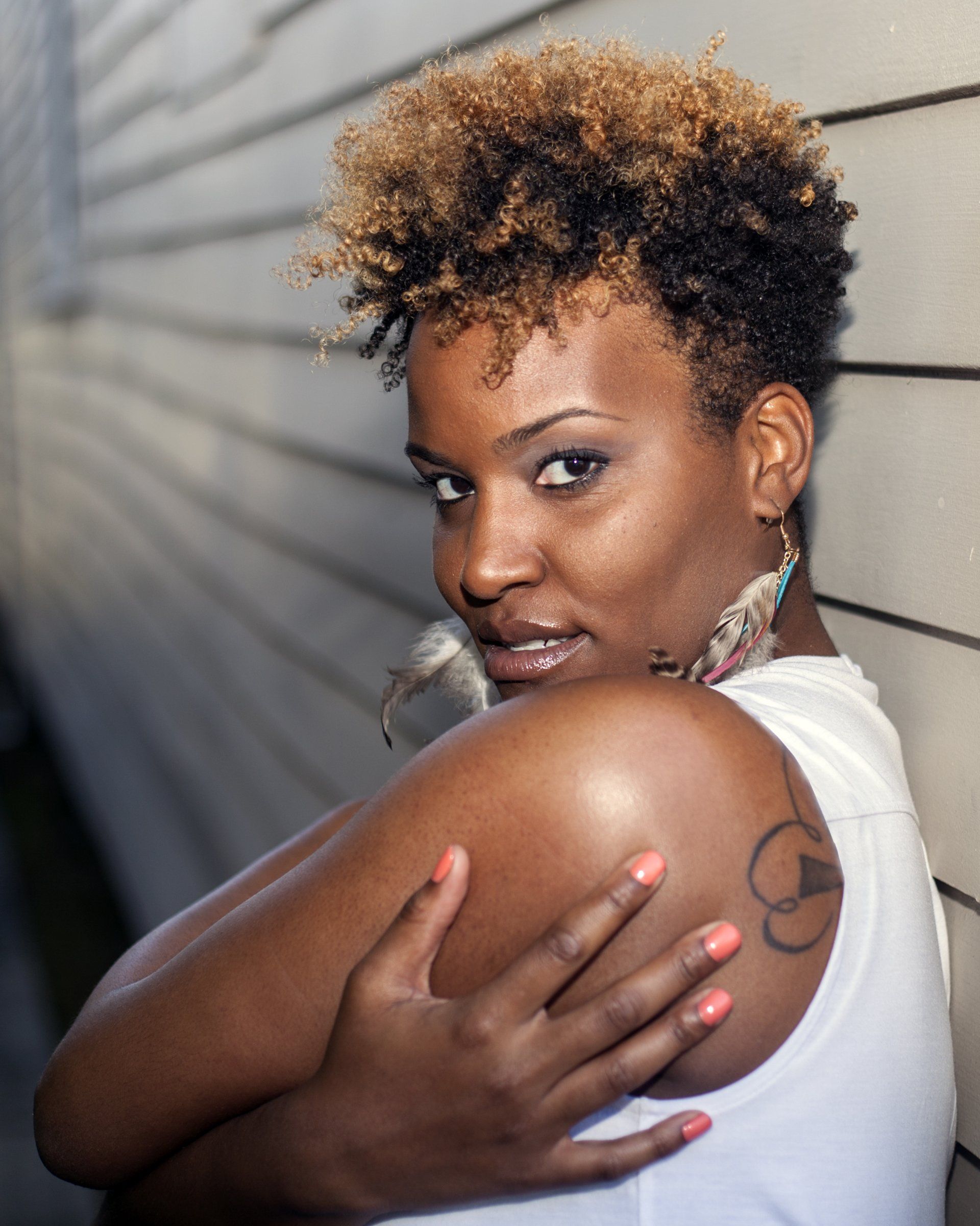 A woman with a tattoo on her arm is hugging herself