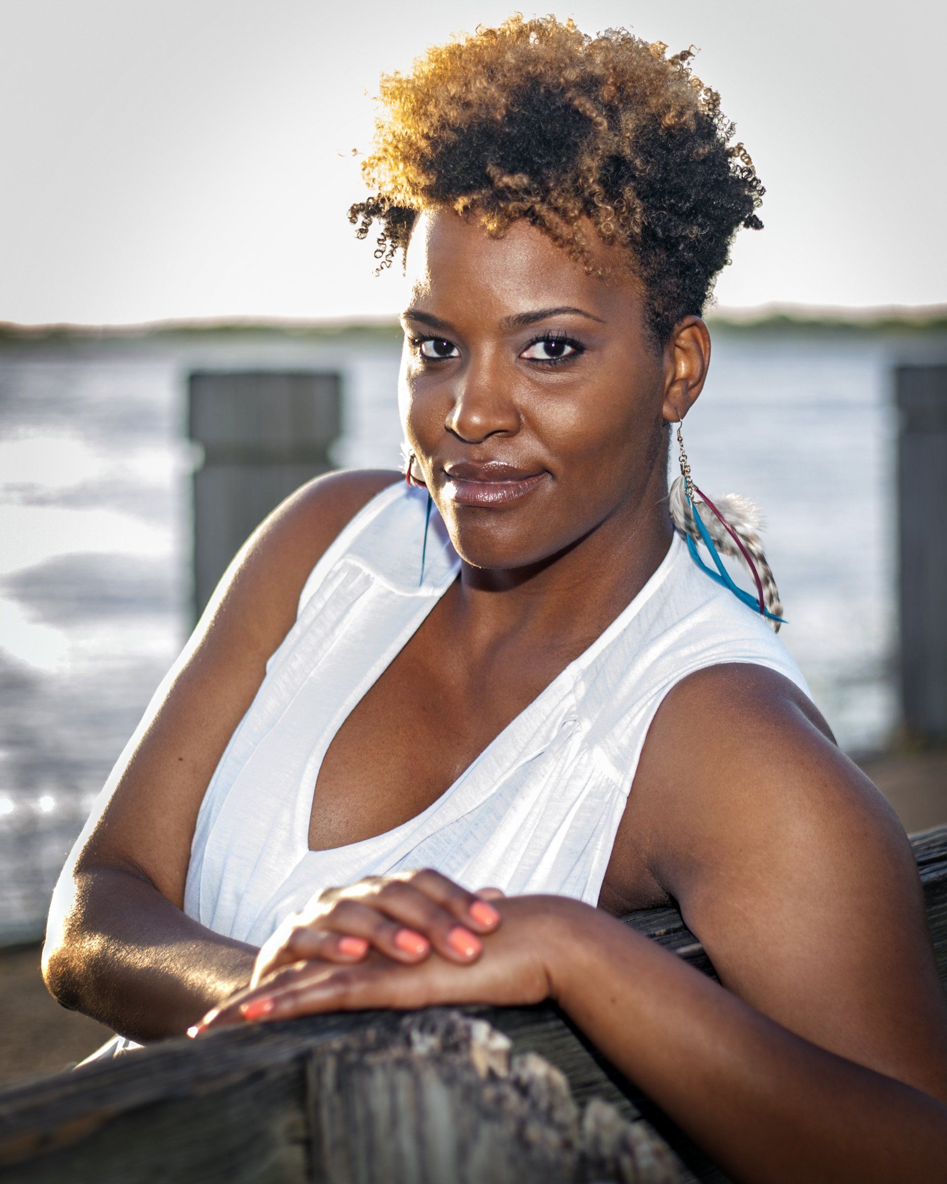 A woman in a white tank top is leaning on a wooden railing