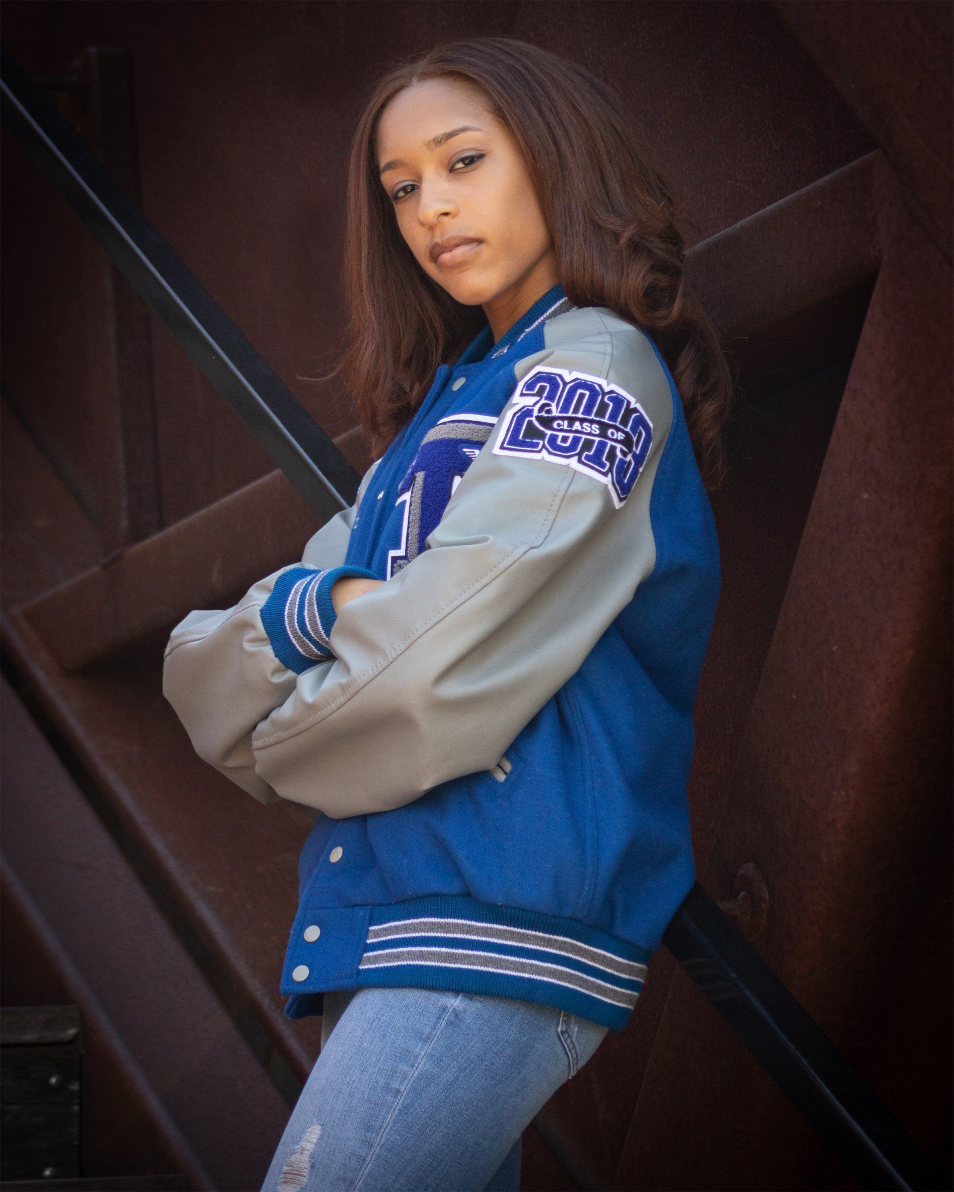 A girl wearing a blue and grey varsity jacket with the letter t on the sleeves
