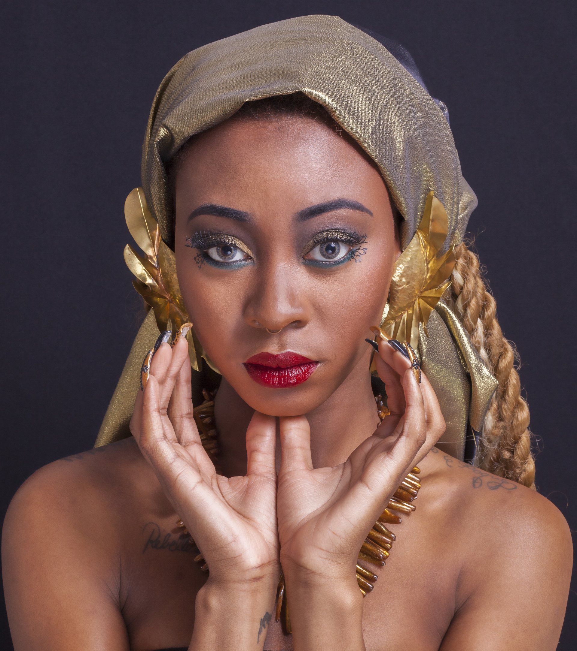 A woman wearing a gold head scarf and gold earrings