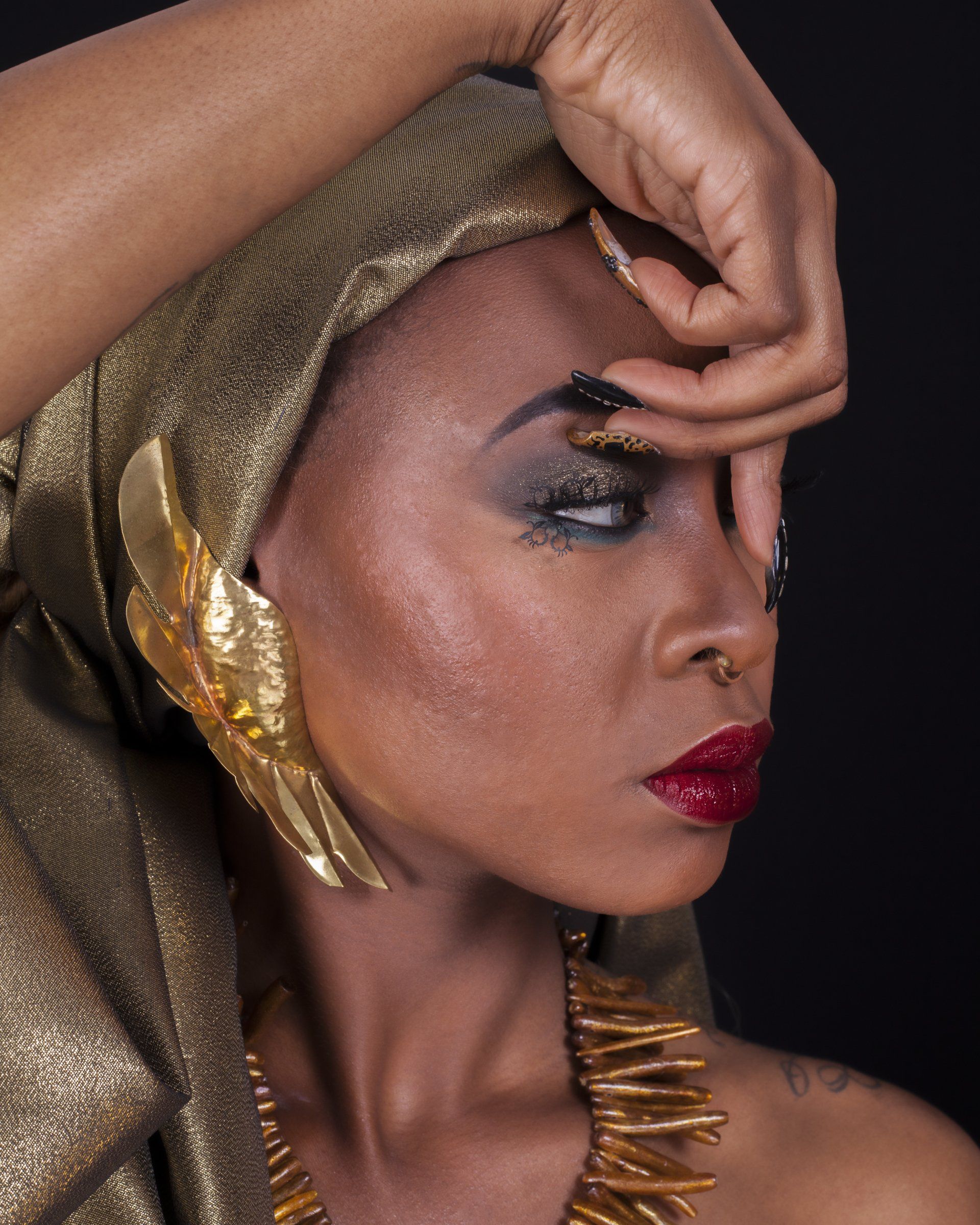 A woman wearing a gold head scarf and a gold necklace