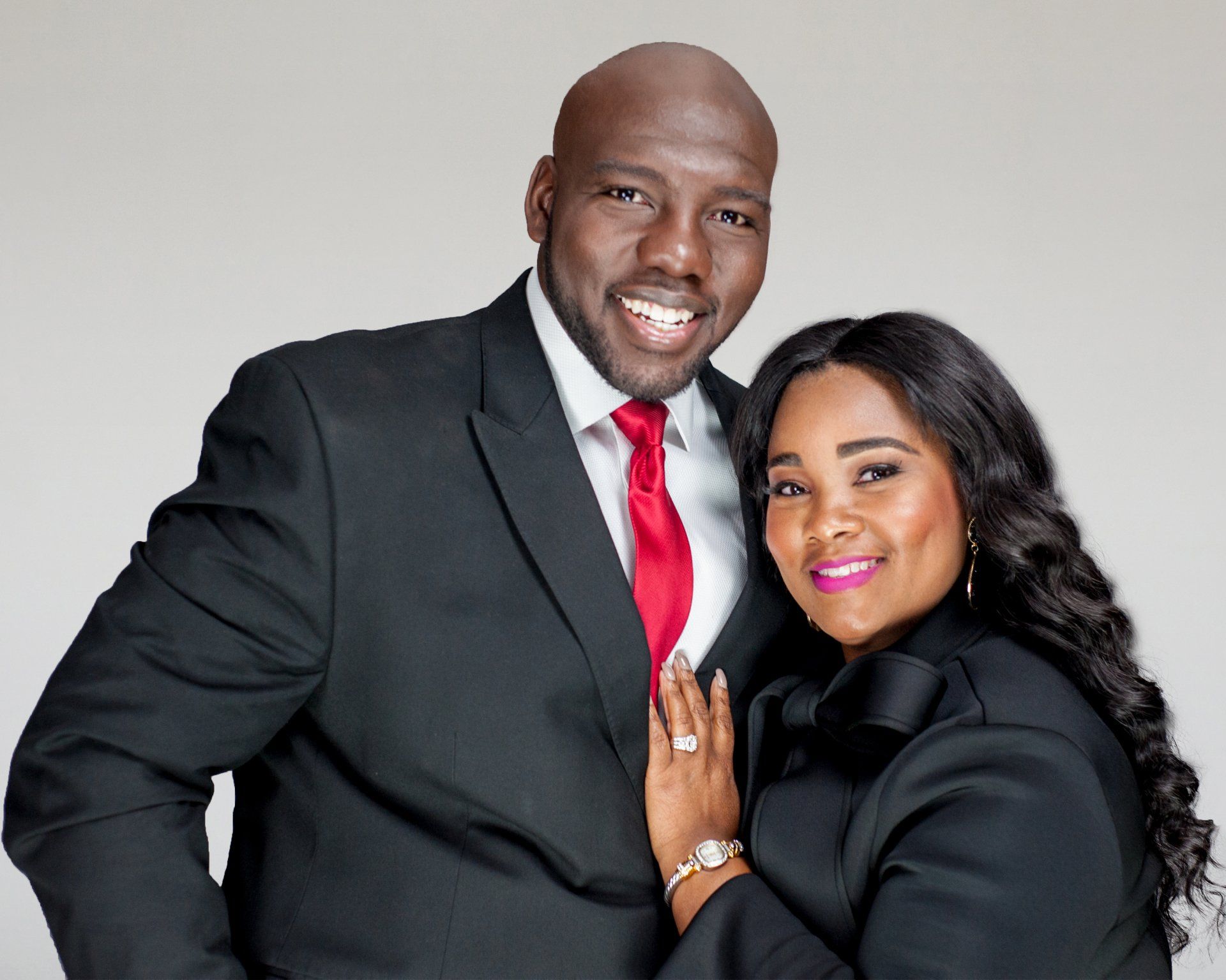 A man in a suit and tie is standing next to a woman in a black jacket.