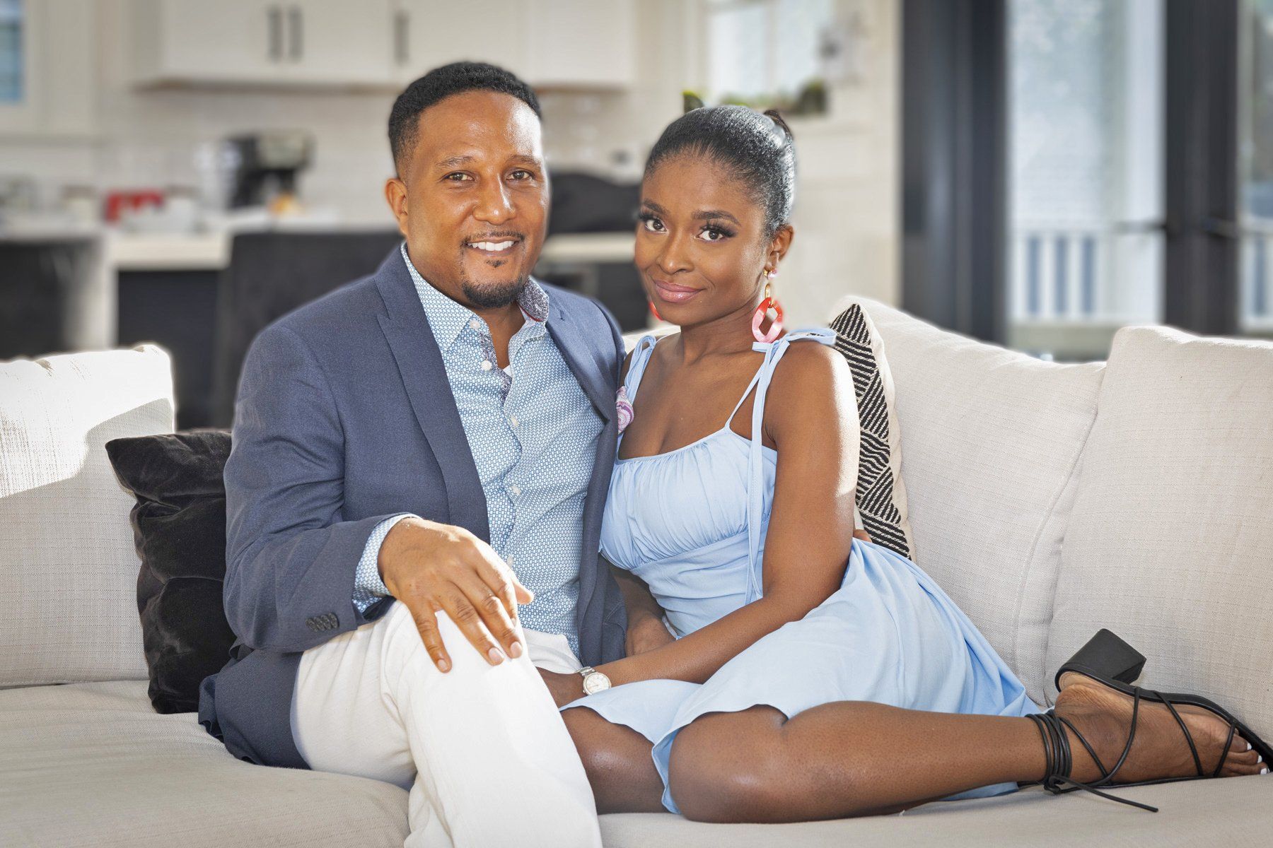 A man and a woman are sitting on a couch posing for a picture.