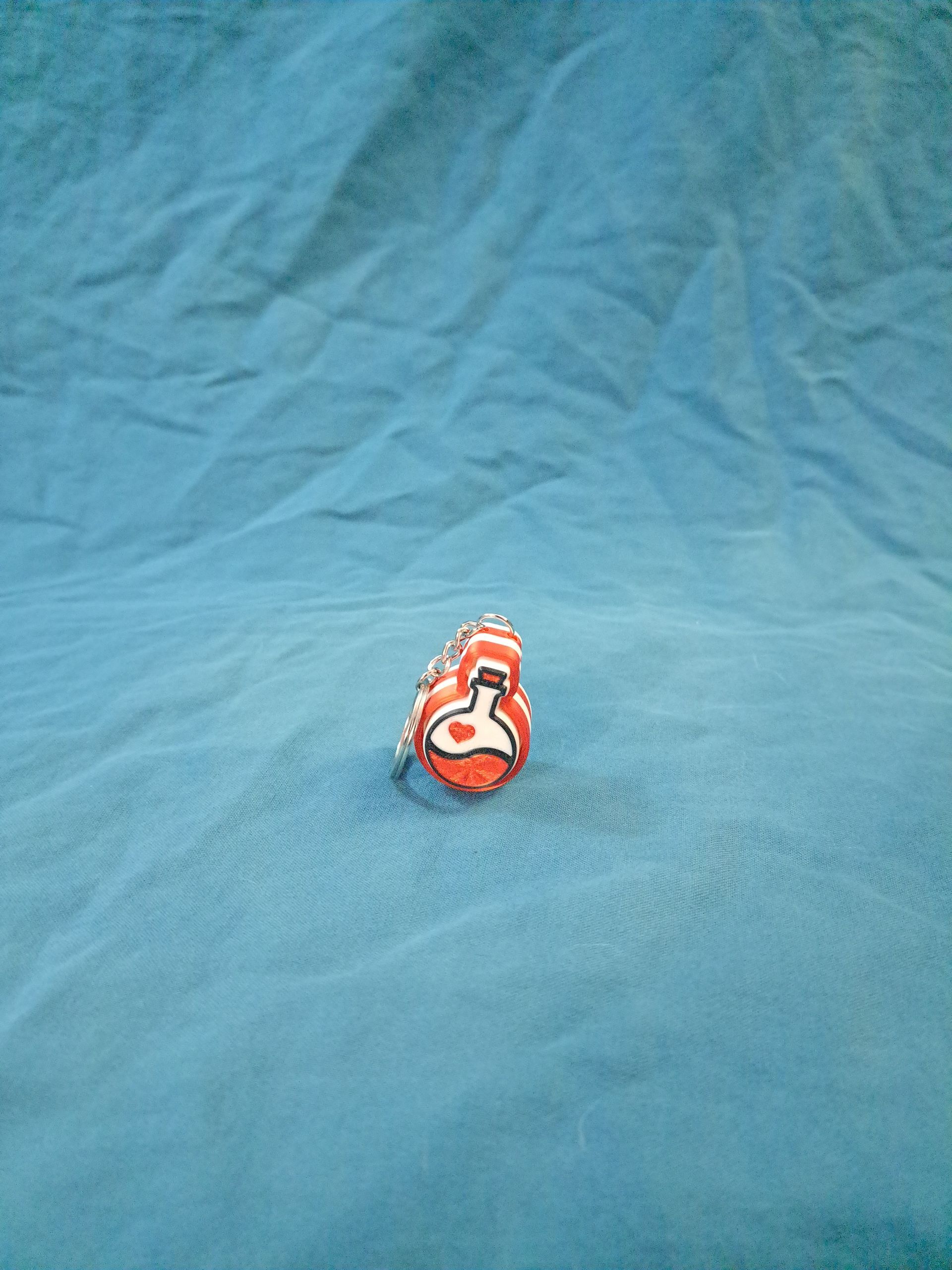 Red and white love potion clicker keychain.
