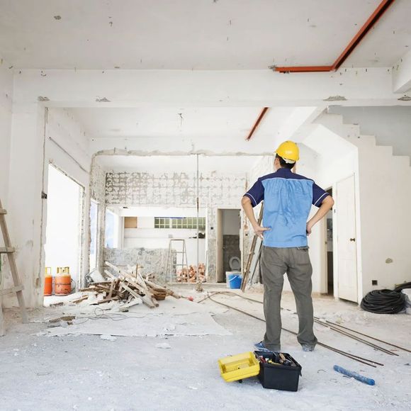 Un homme portant un casque est debout dans une pièce en construction
