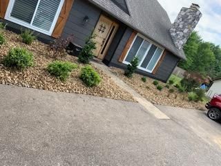 Dark gray house with landscaping and a driveway.