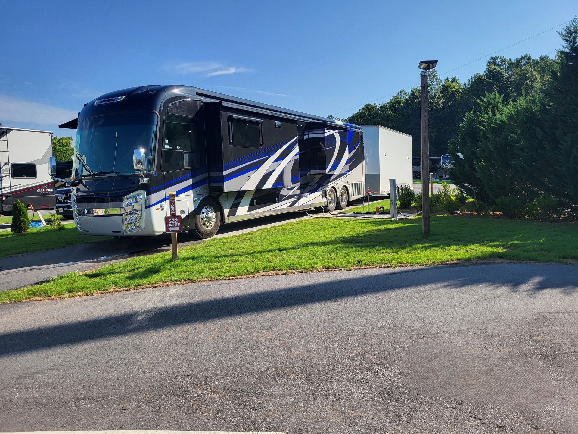 A large blue and white rv is parked on the side of the road.