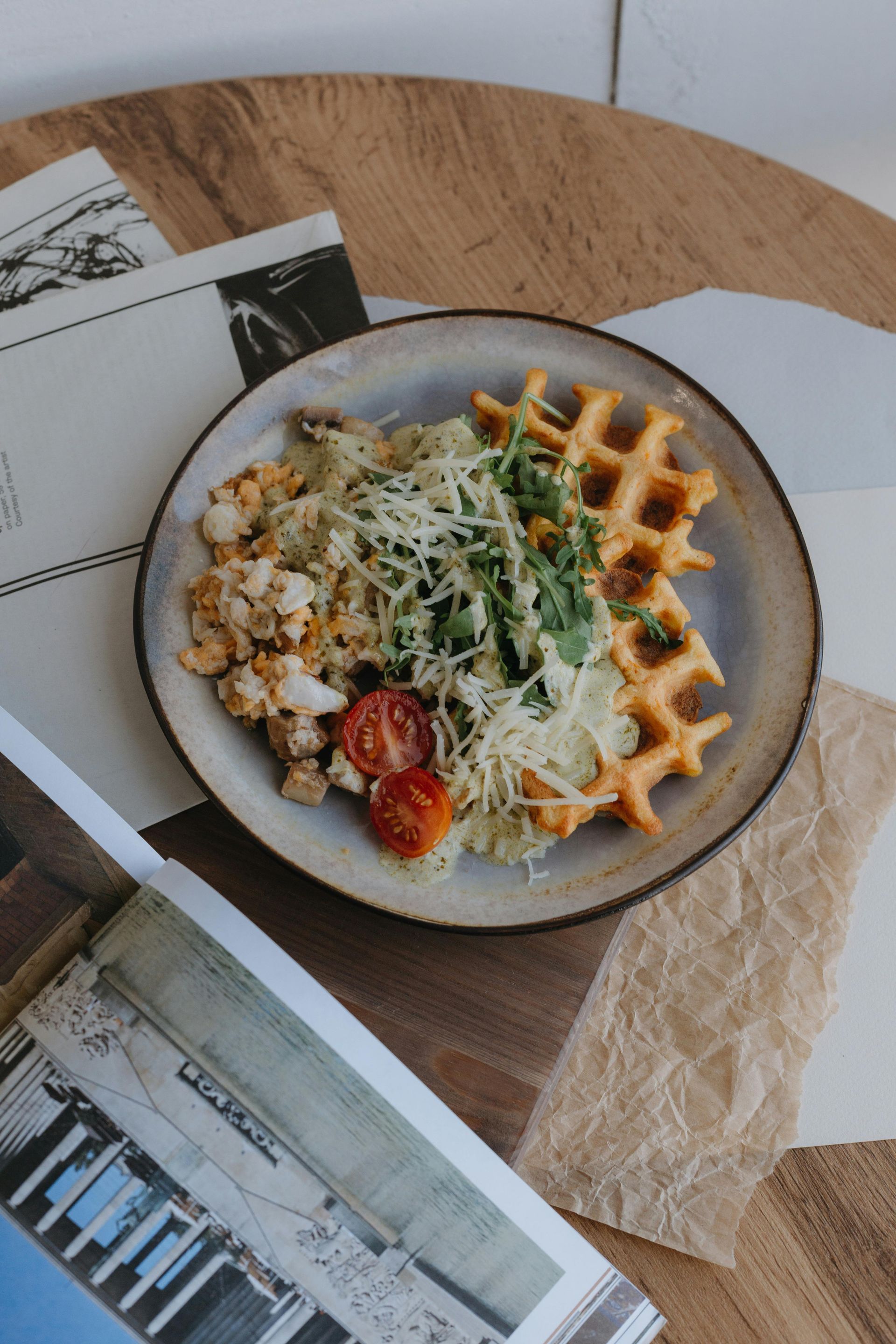 A plate of food is sitting on a wooden table next to a book.