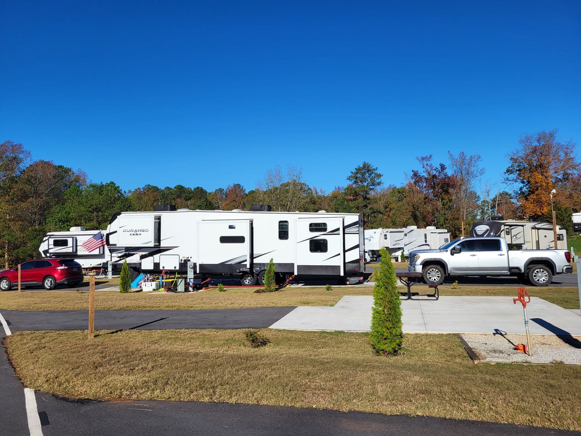 A group of rvs are parked in a campground on a sunny day.