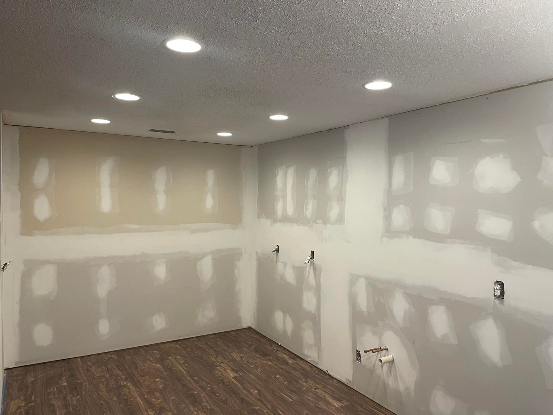 A room with drywall on the walls and a wooden floor.