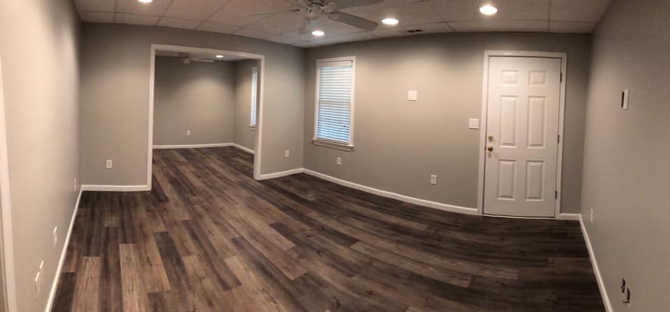 A large empty room with hardwood floors and a ceiling fan.