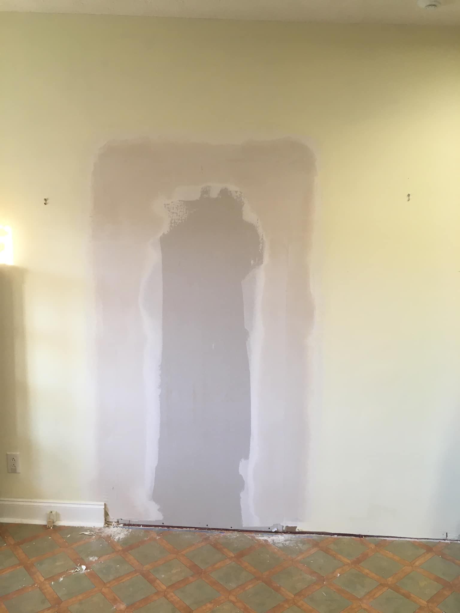 There is a repaired hole in the wall in the middle of the room.