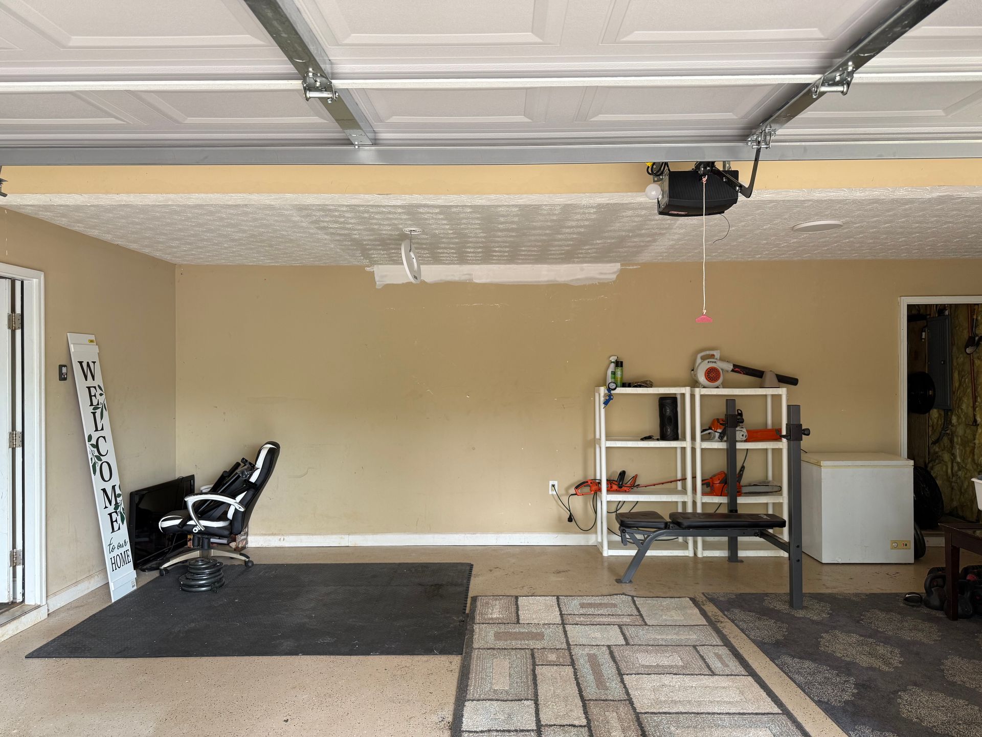 A garage with a lift and a chair and a rug.