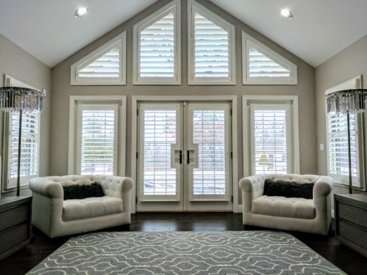 A living room with a large window and black panel blinds.
